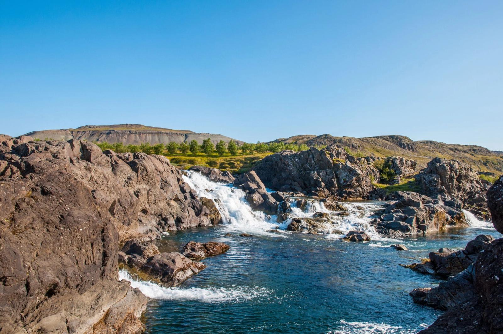 Glanni Waterfall flowing through dark lava rock near Bifröst in West Iceland.