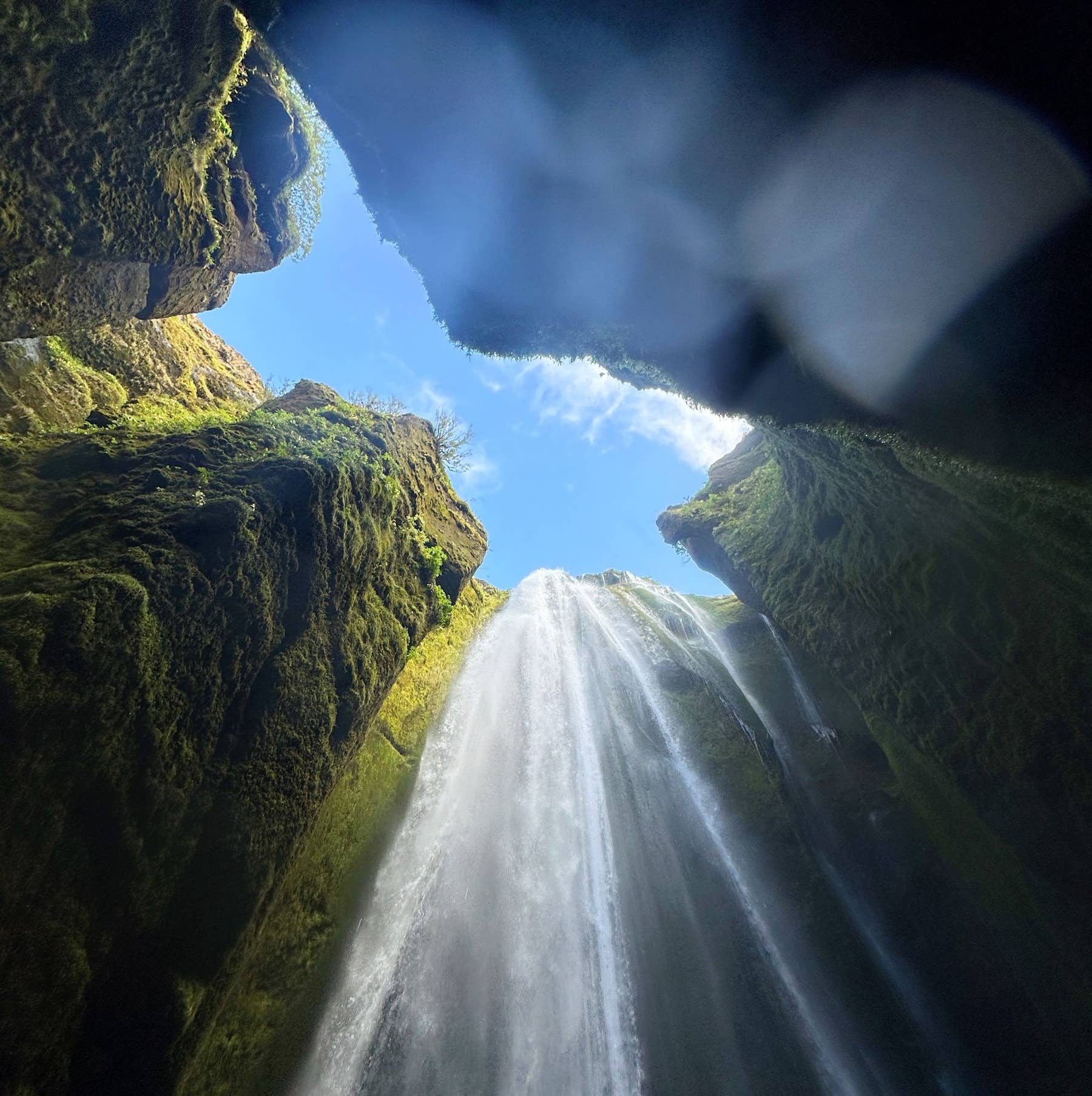 Light and spray inside the narrow Gljúfrabúi waterfall canyon.
