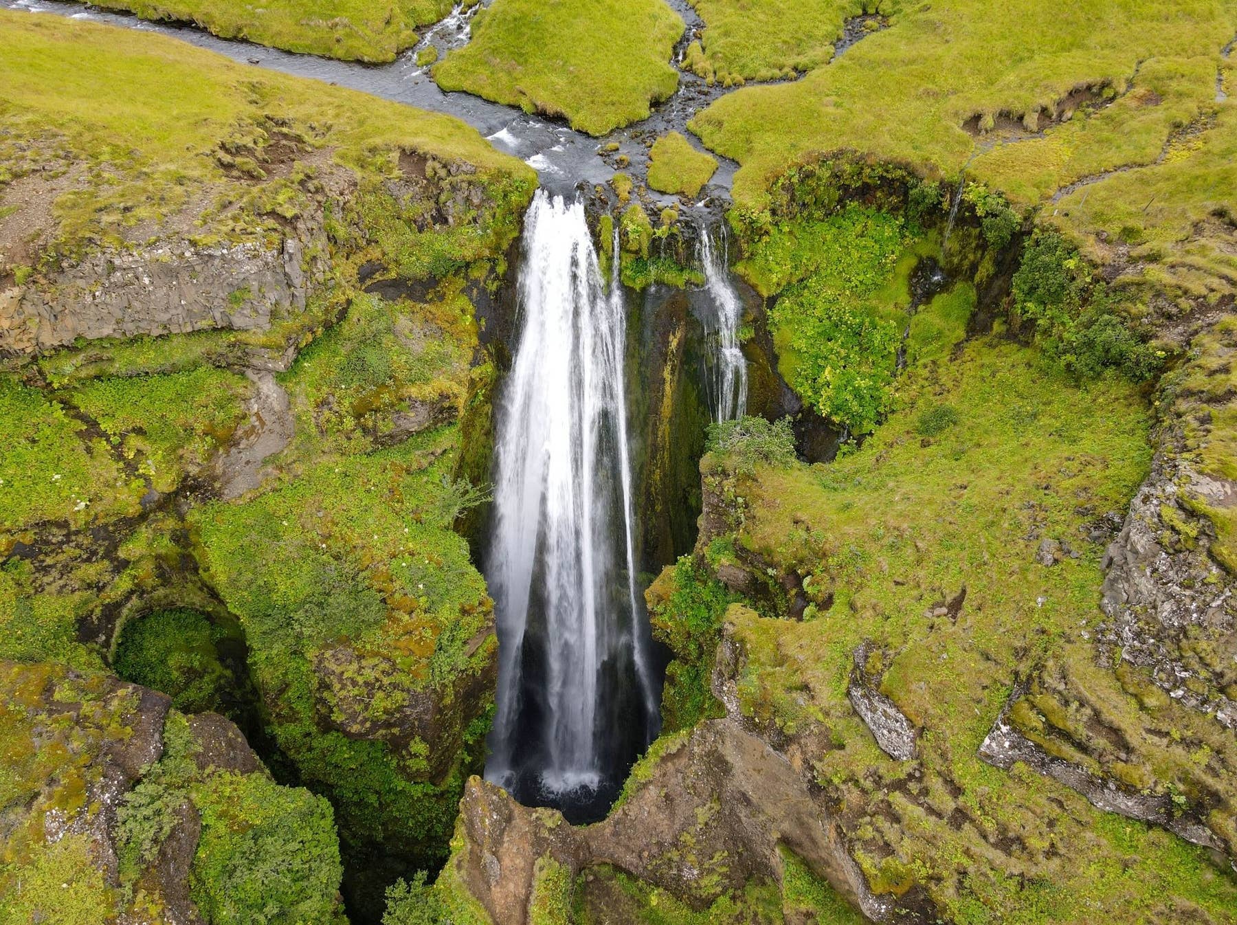 Gljúfrabúi waterfall and mossy canyon walls seen from above the cleft.