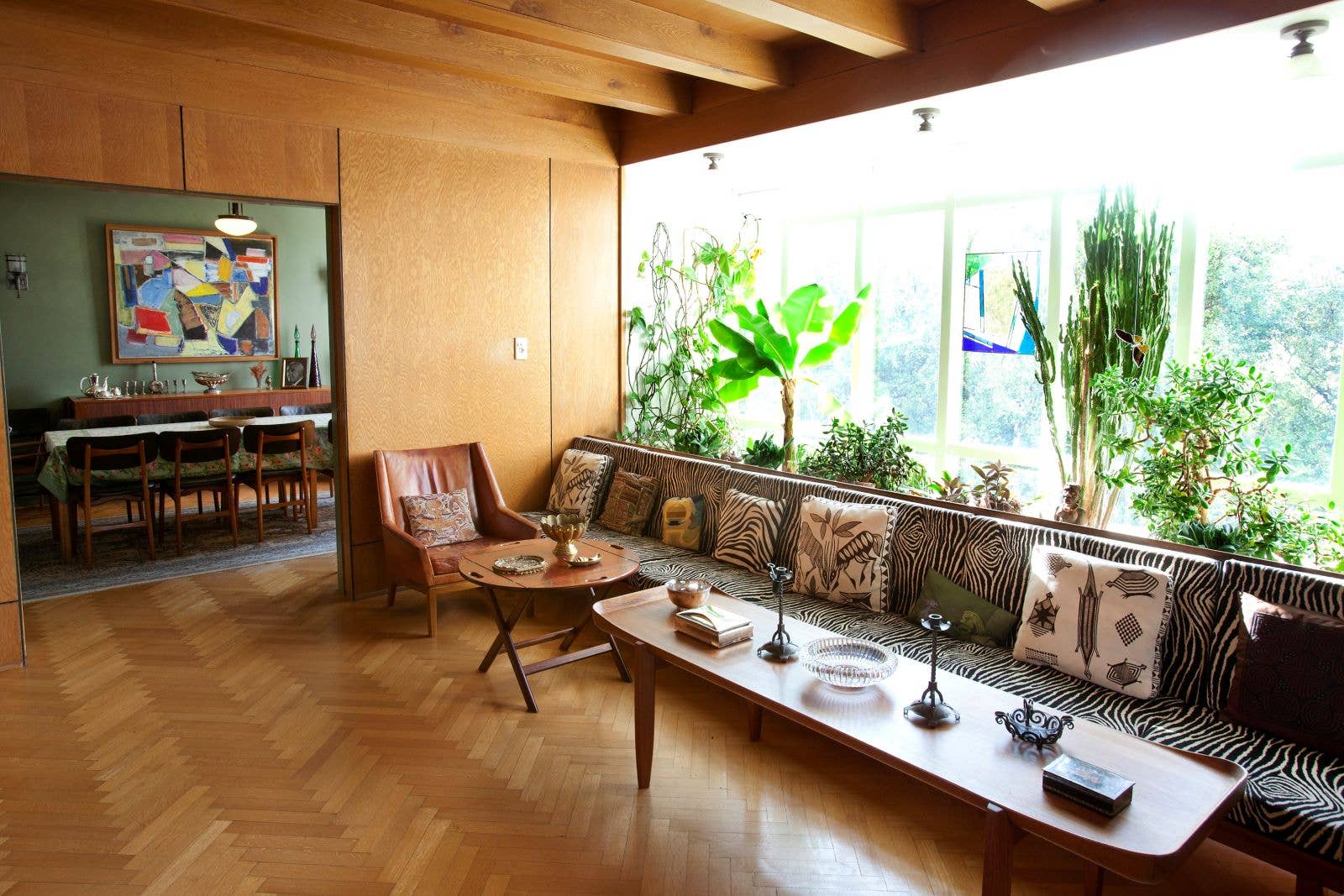 A preserved living room inside Gljúfrasteinn with wood walls, plants, art, and mid-century furniture.