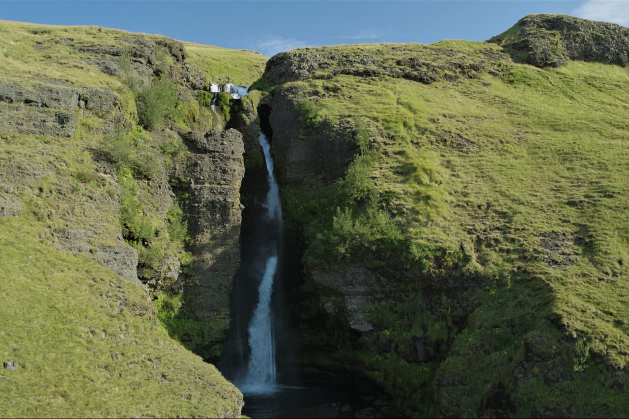 Gluggafoss waterfall dropping through green tuff cliffs in Fljótshlíð, South Iceland.