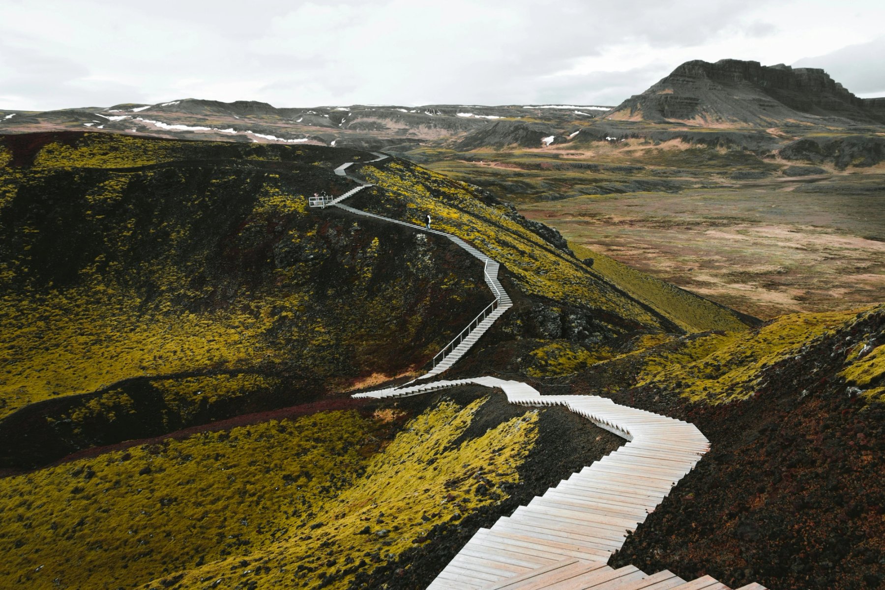 Wooden stairs crossing the dark and mossy slopes of Grábrók crater in West Iceland.