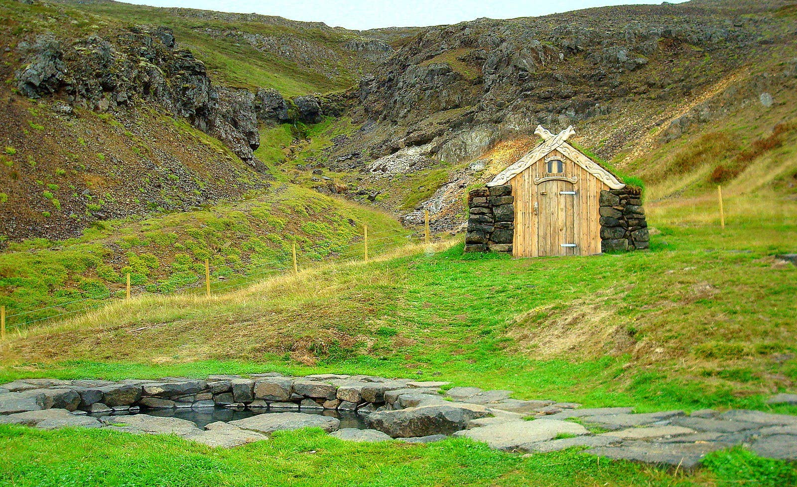 Guðrúnarlaug stone hot-spring pool and turf-roofed changing hut in Sælingsdalur.