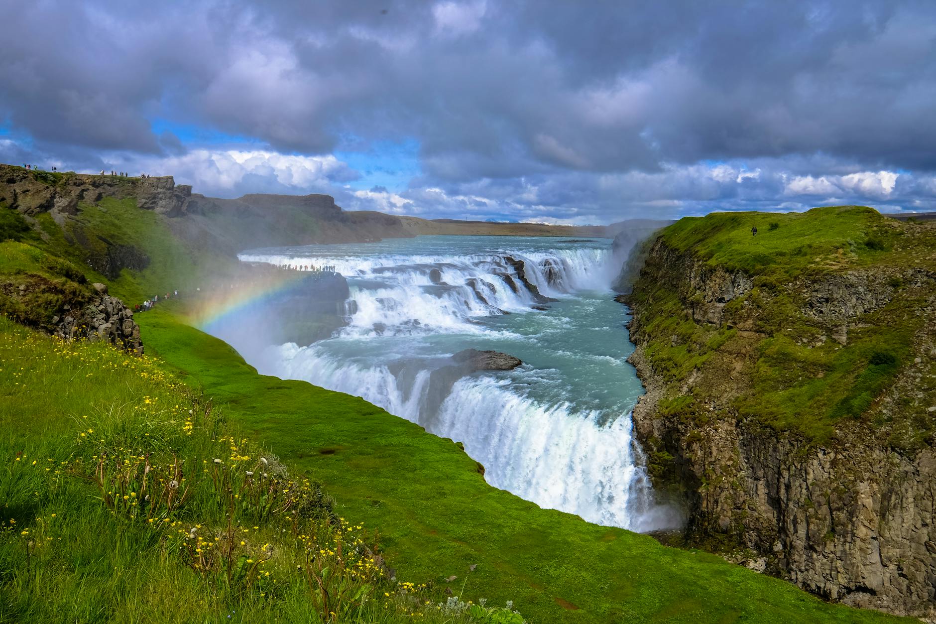 Close view of Gullfoss water dropping through mist and dark canyon rock.
