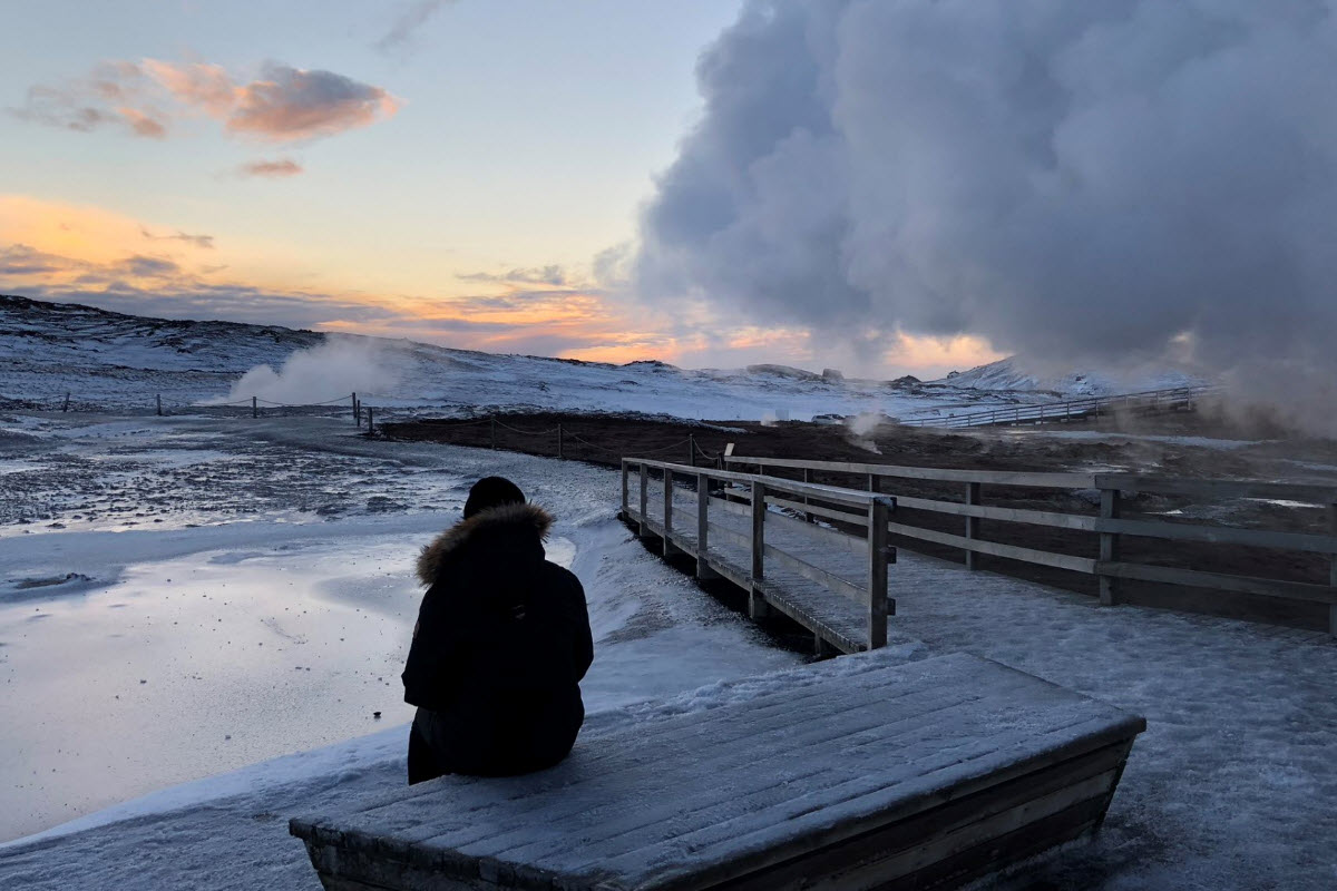 Snowy Gunnuhver boardwalks with steam drifting across the geothermal field at low light.