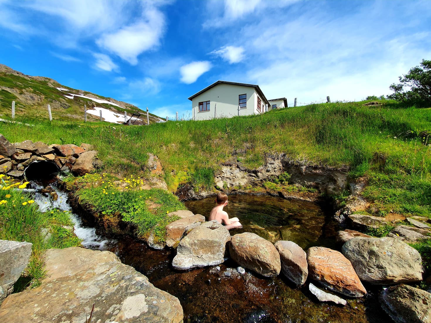 Creek-fed Gvendarlaug hot pool below Laugarhóll in summer.