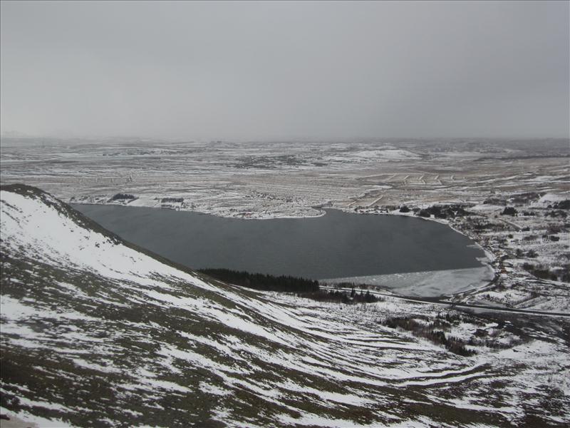 Hafravatn below the snowy side of Hafrafell with Mosfellsbær roads beyond.