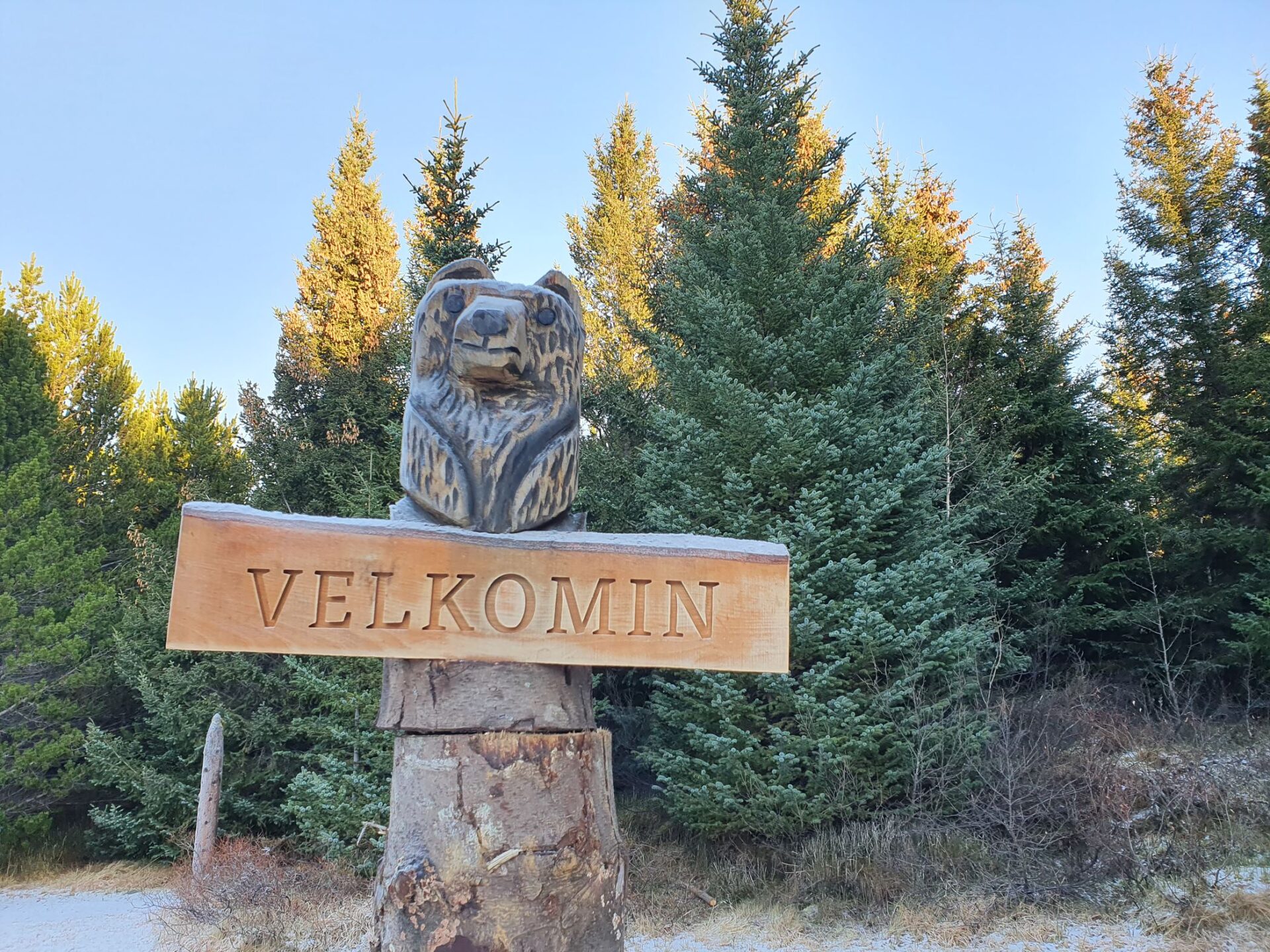 Wooden welcome sign at Heiðmörk with evergreen trees and patches of winter snow.