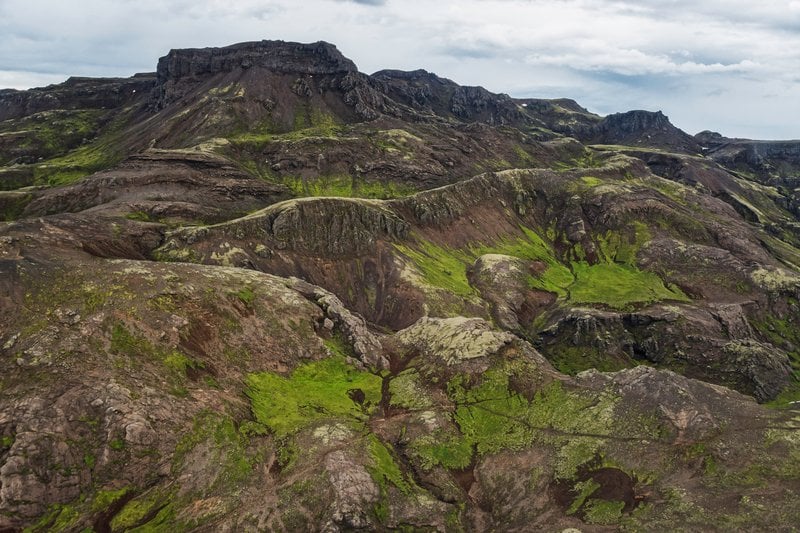 Wide green and black Hengill mountain slopes with lava ridges and mossy ground.