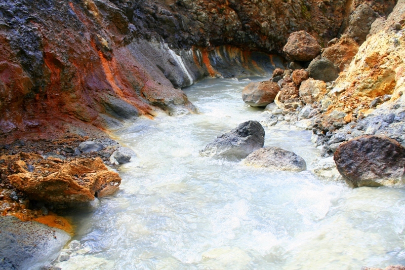 Milky geothermal water between red and dark rocks in Hveragil near Innstidalur.