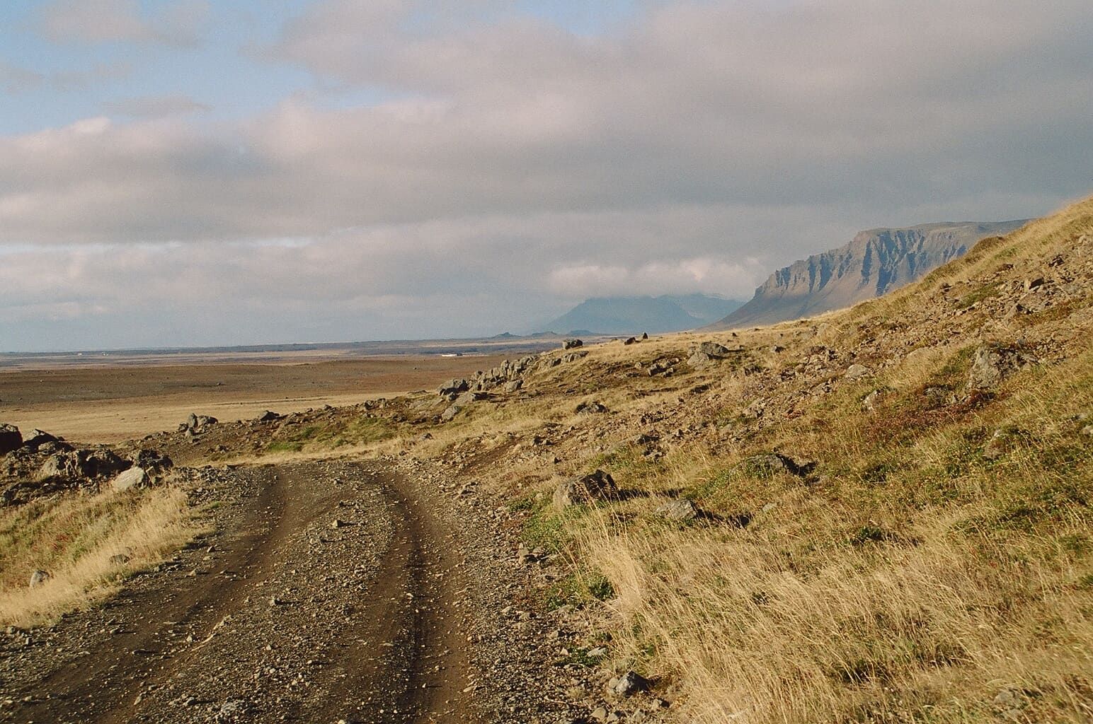 A rough gravel track leading into Hítardalur with mountains and open valley country ahead.