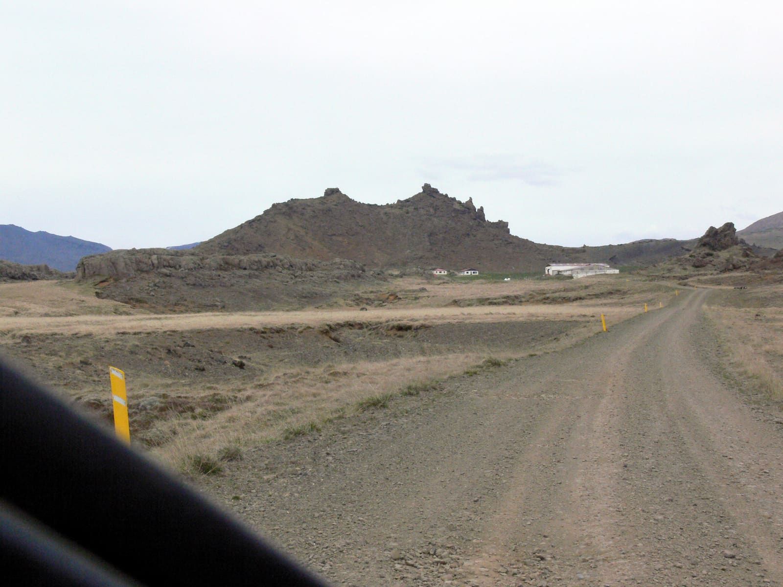 Rocky slopes and farm buildings below Bæjarfell in Hítardalur valley.