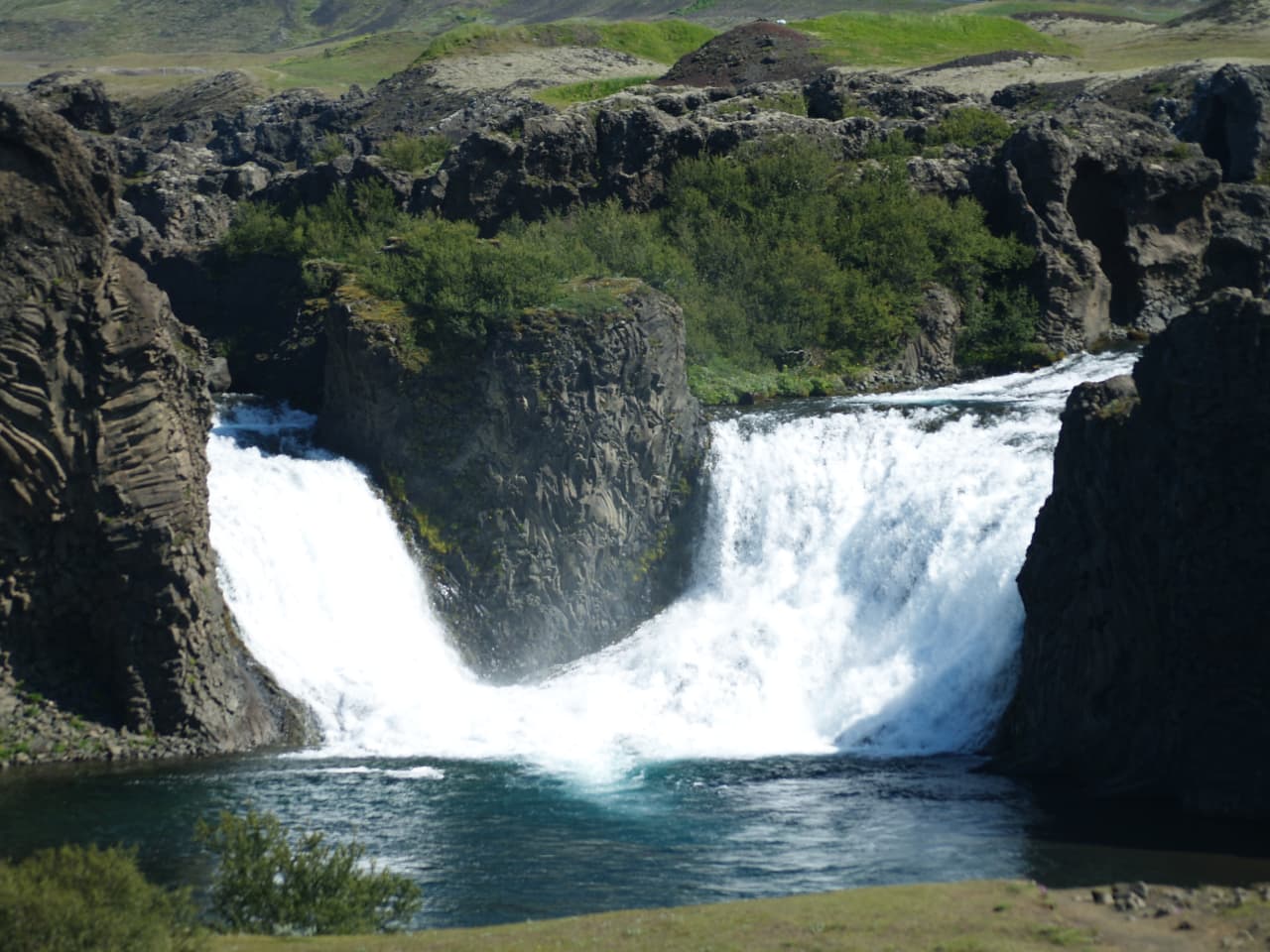 Close view of Hjálparfoss splitting around dark basalt formations in South Iceland.