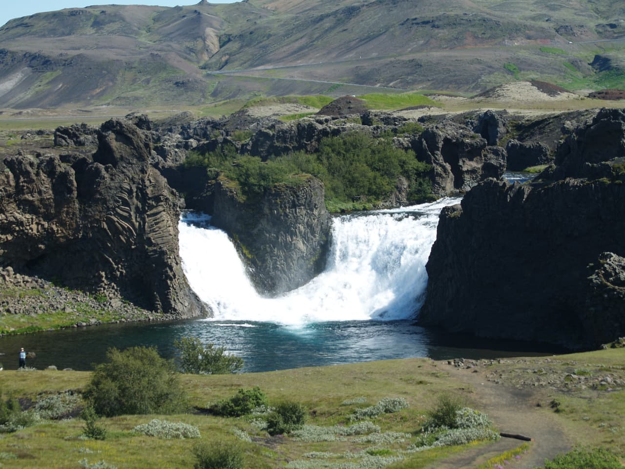 Hjálparfoss seen from above with the split waterfall, basalt rocks, and Þjórsárdalur landscape.
