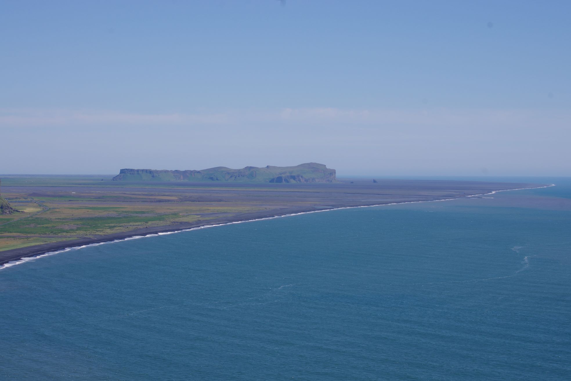 Hjörleifshöfði rising from dark South Coast sands with the sea beyond
