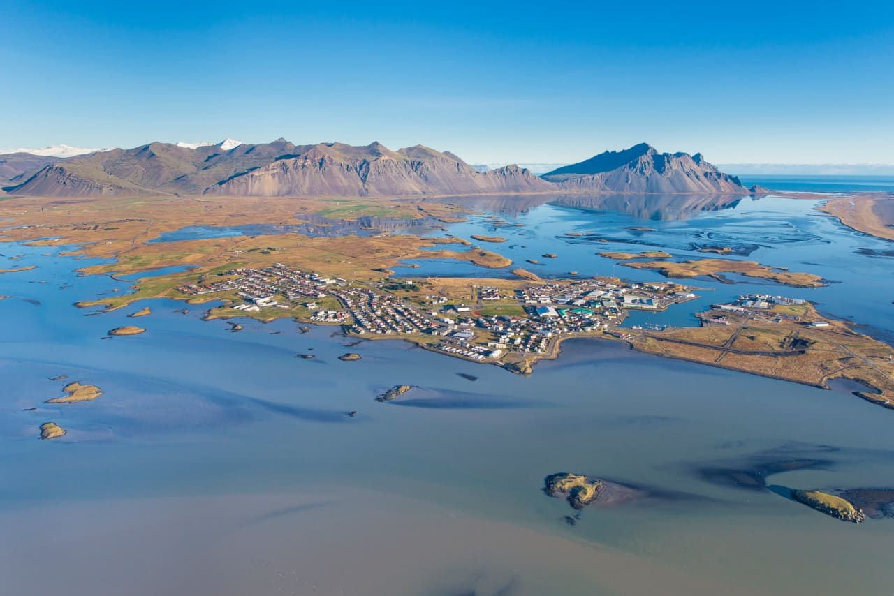 Aerial view of Höfn harbor, town buildings, water, and mountains in southeast Iceland.