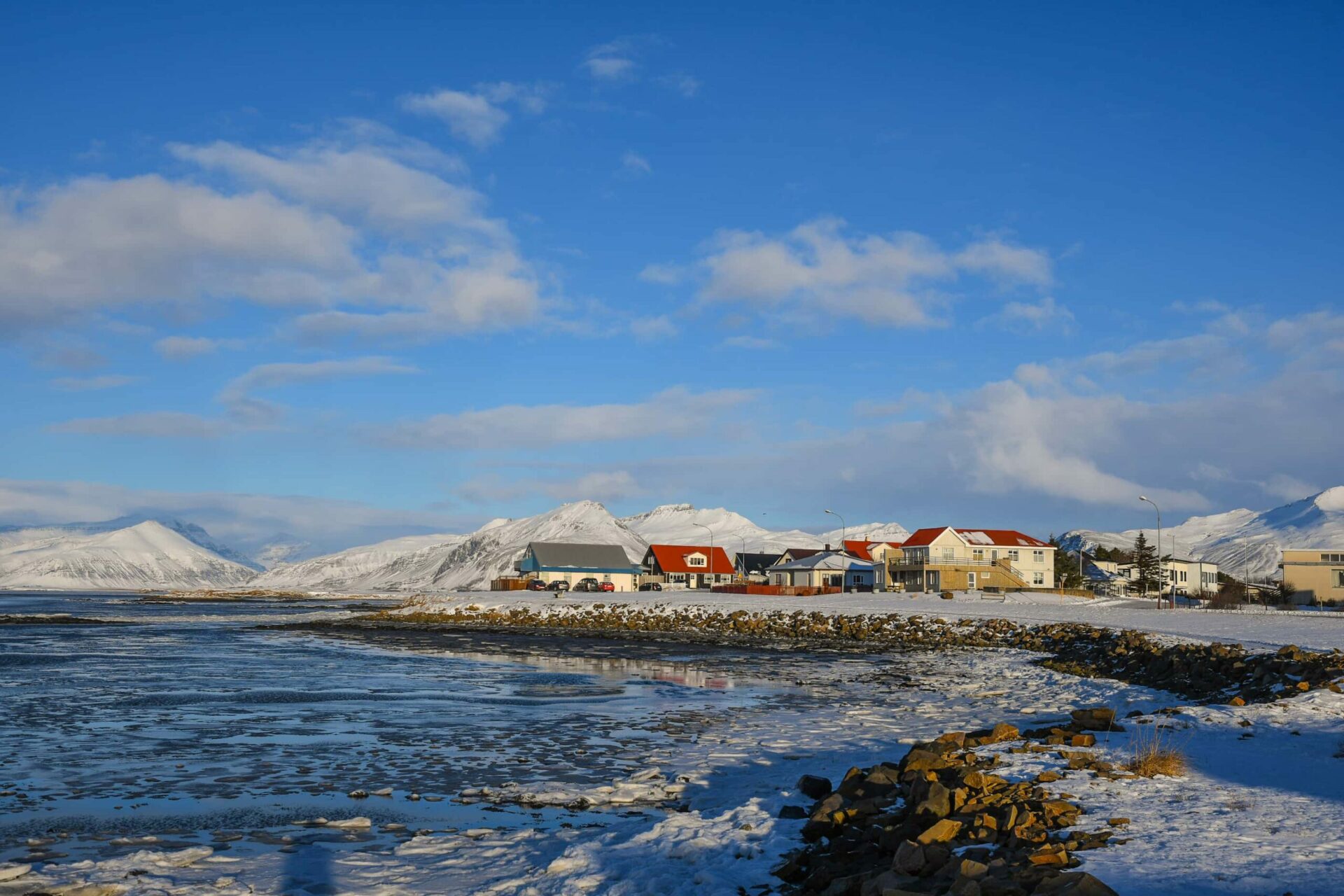 Snow-covered Höfn waterfront with mountains and water beside the town.