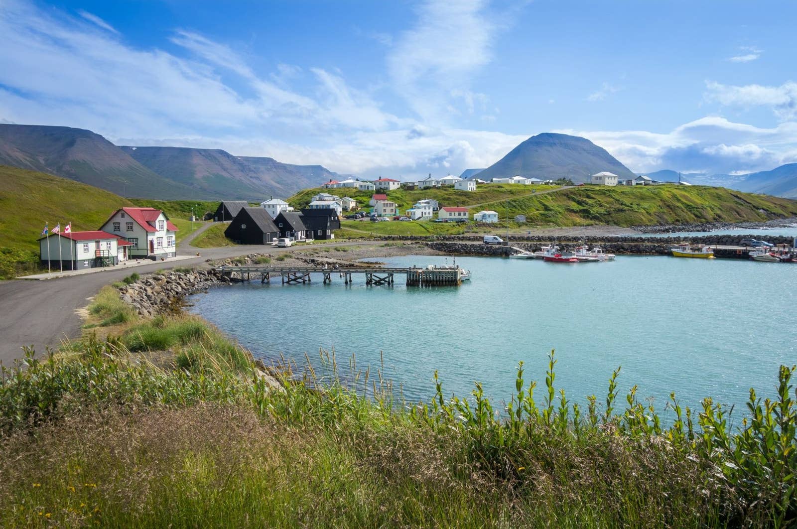 Hofsós harbor and village houses on the edge of Skagafjörður with mountains behind the water.