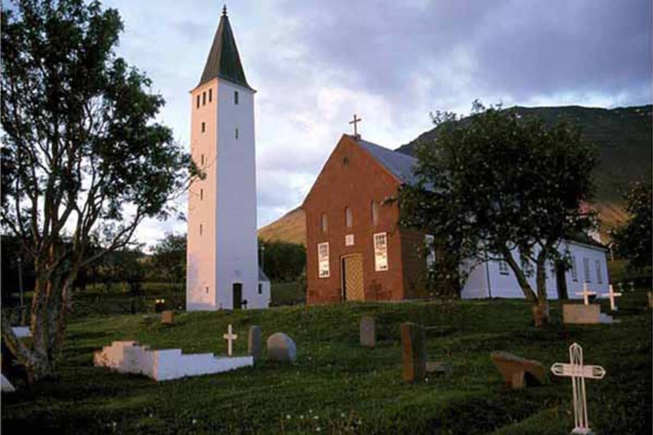 Hólar Cathedral and its white tower seen from the churchyard in Hjaltadalur.