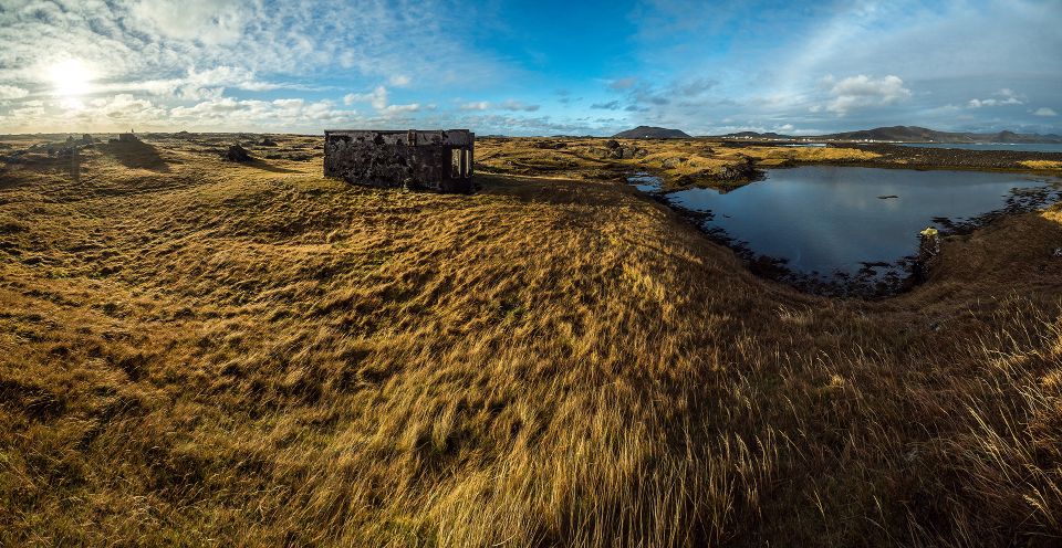 Old coastal ruins beside a small lagoon and windswept grass at Hópsnes near Grindavík.