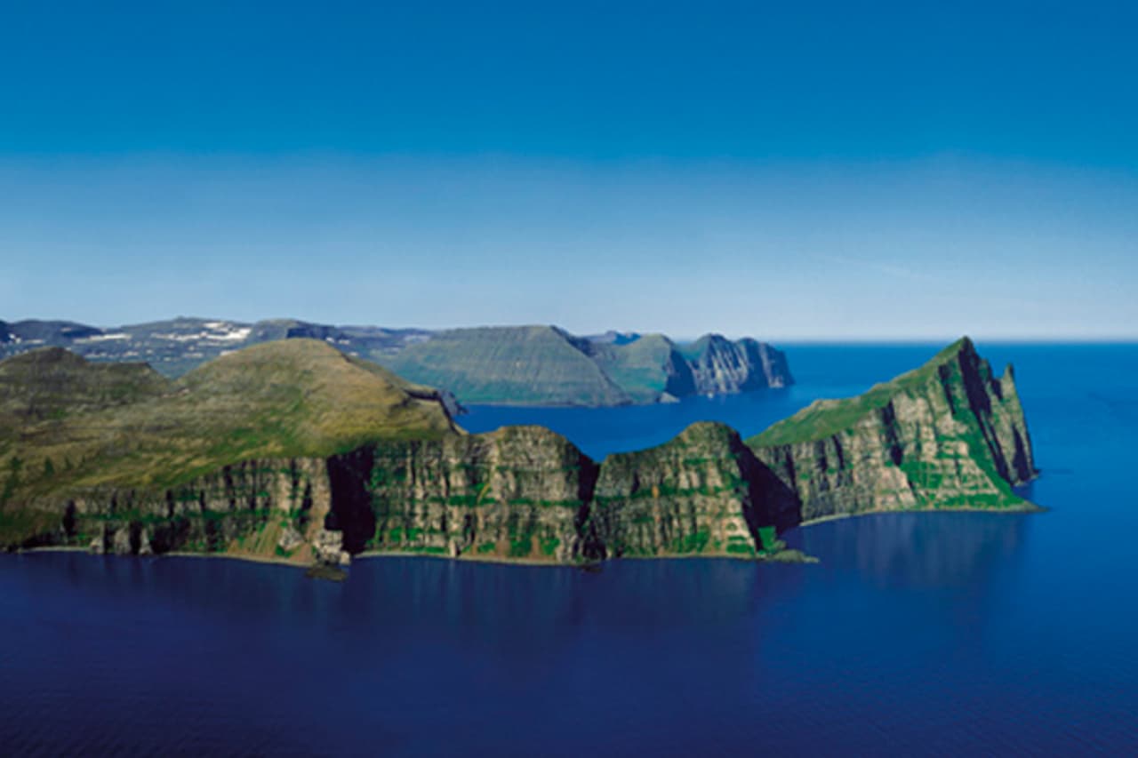 Wide view of the Hornbjarg sea cliffs rising above the water in Hornstrandir.