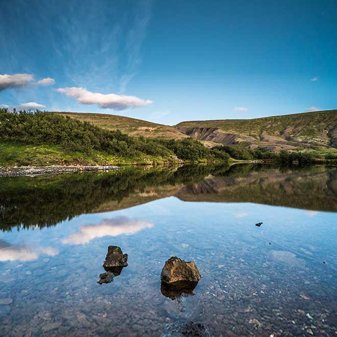 Still water reflecting the hills and sky near Húsafell in West Iceland.