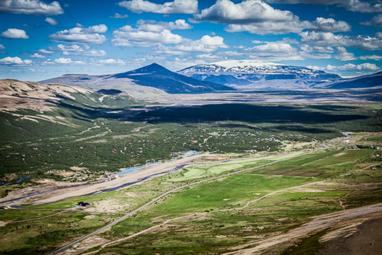 Húsafell valley with birch woodland, buildings, roads, mountains, and glacier views in West Iceland.