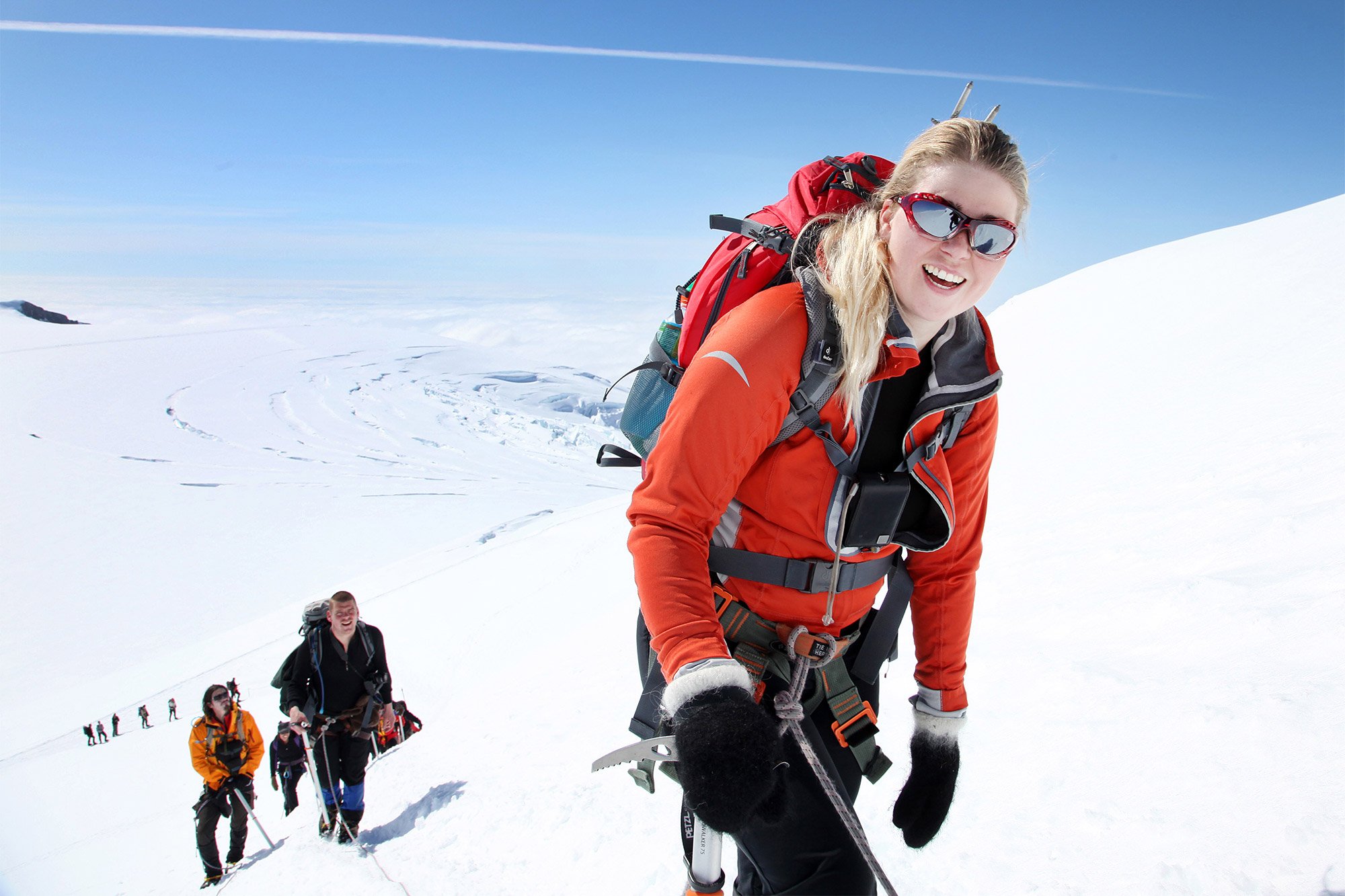 Roped climbers ascending a snow slope on Hvannadalshnúkur with glacier ice below.