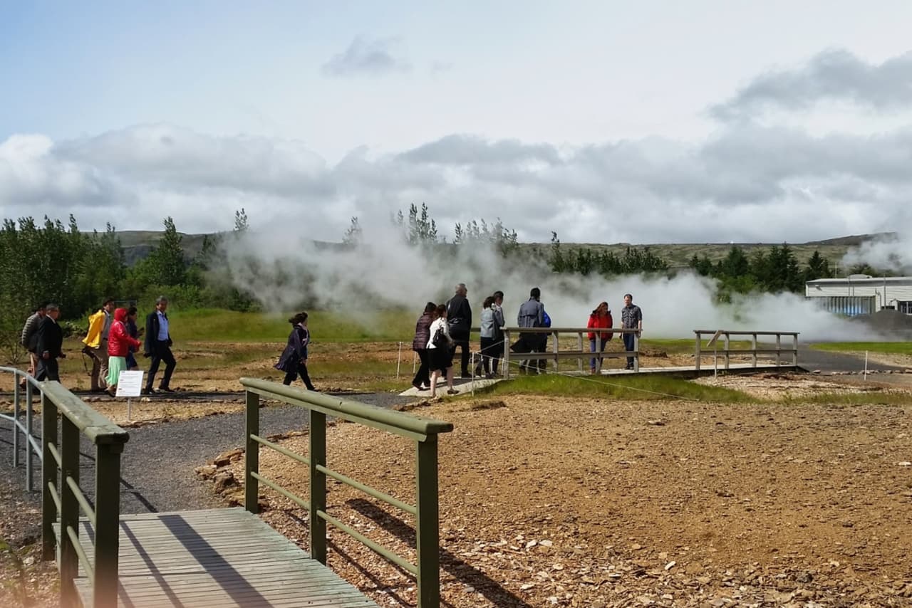 Visitors walking on a marked path beside steam in the Geothermal Park in Hveragerði.