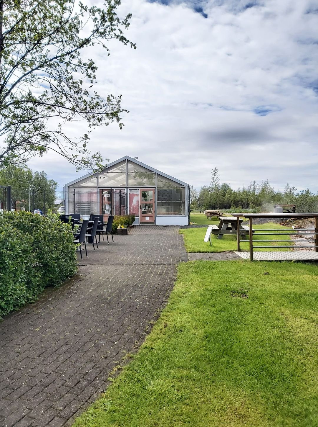 A path leading through greenery toward a greenhouse area in Hveragerði.