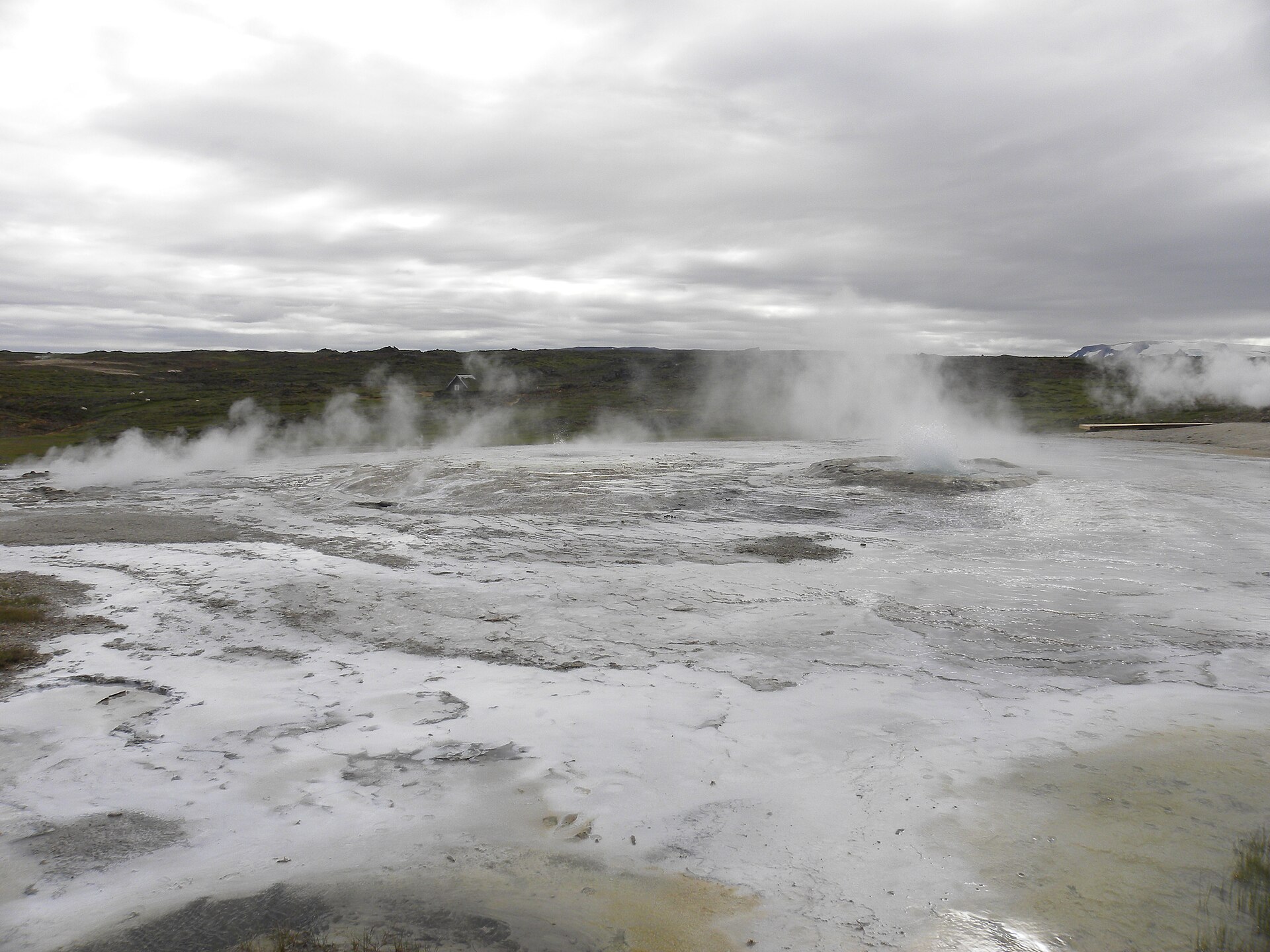 Steam rising from pale geothermal ground at Hveravellir under low grey highland clouds.