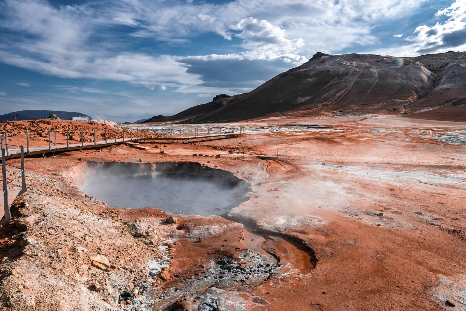 Steaming mud pool and boardwalk at Hverir below the slopes of Námafjall in North Iceland.