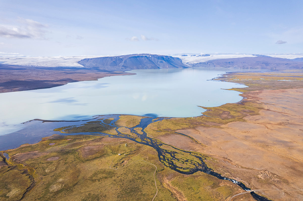 Hvítárvatn shoreline with Langjökull glacier and bare highland slopes beyond the water.