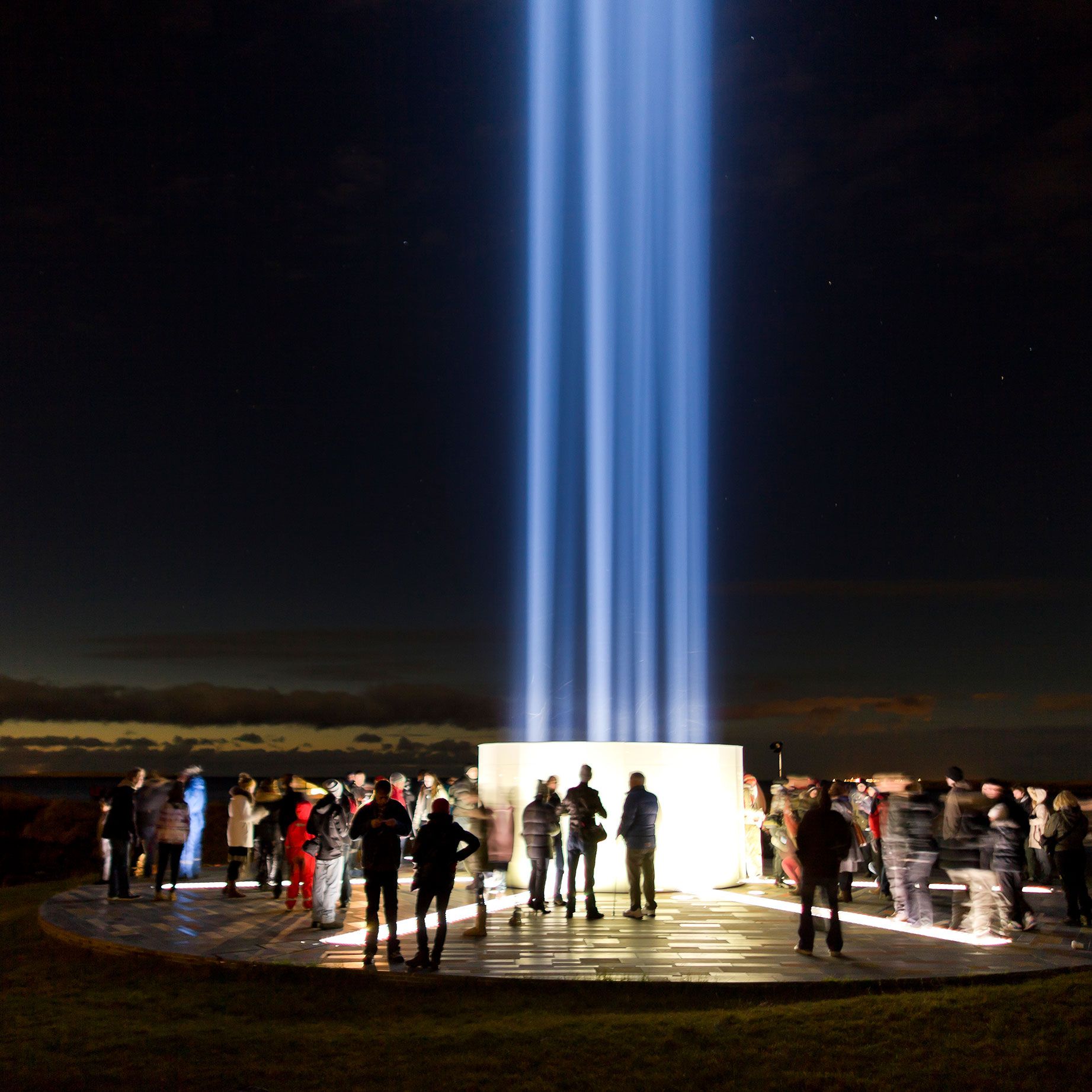 People gathered by the illuminated Imagine Peace Tower on Viðey