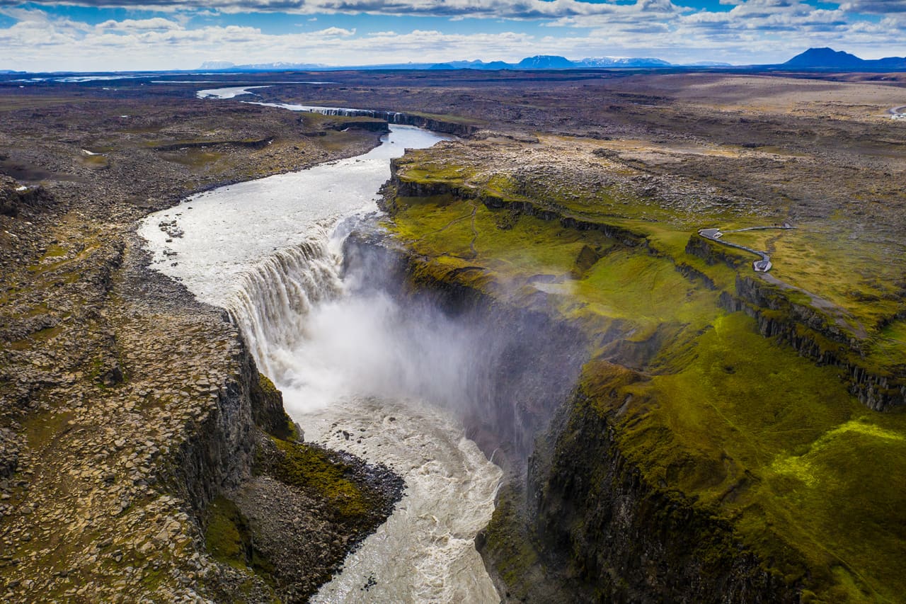 Dettifoss dropping into the Jökulsárgljúfur canyon with the river and road visible nearby.