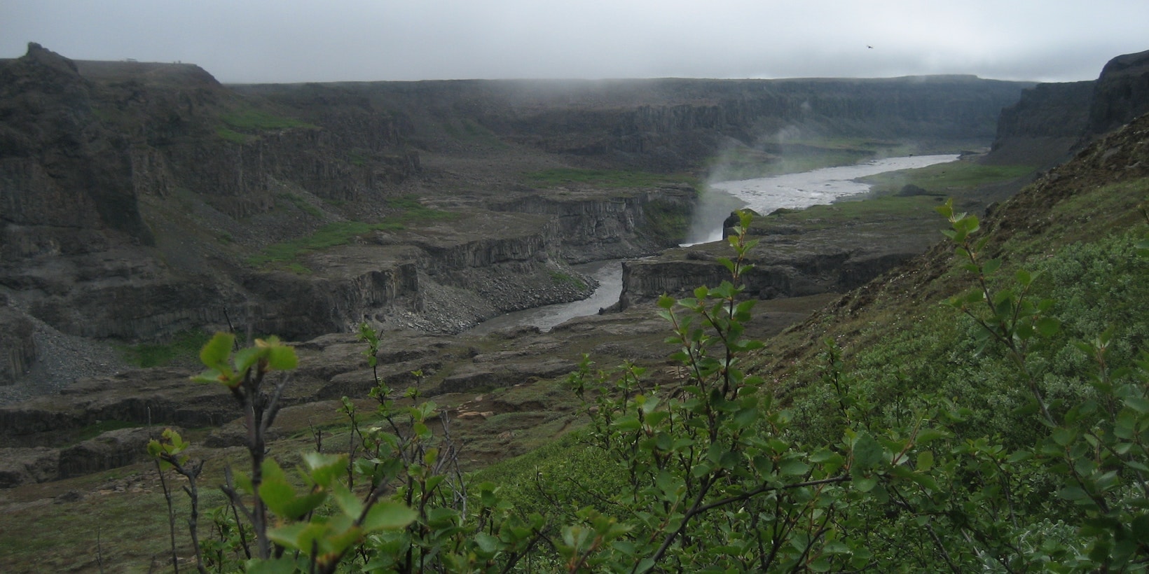 Wide view across Jökulsárgljúfur canyon near Hafragilsfoss with cliffs, river, and mist in North Iceland.