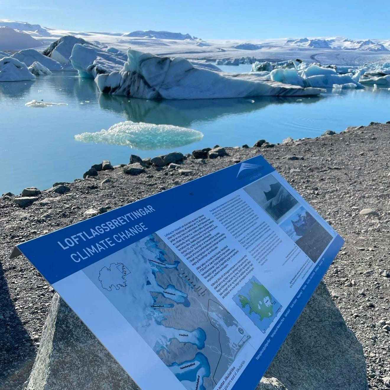 Interpretive sign beside Jökulsárlón Glacier Lagoon with icebergs in the background.