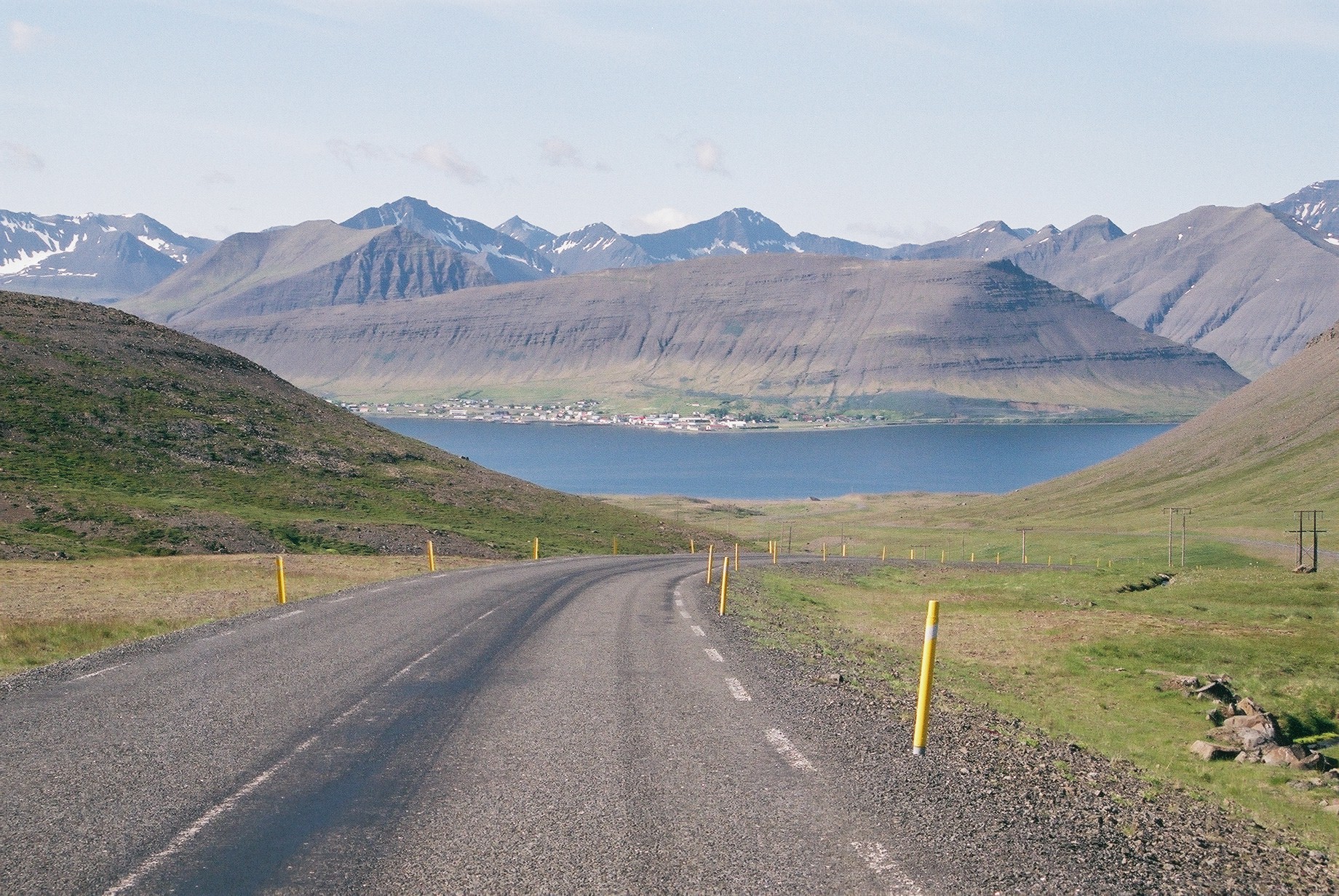 Westfjords road descending toward a fjord with sharp mountains in the Kaldbakur area.