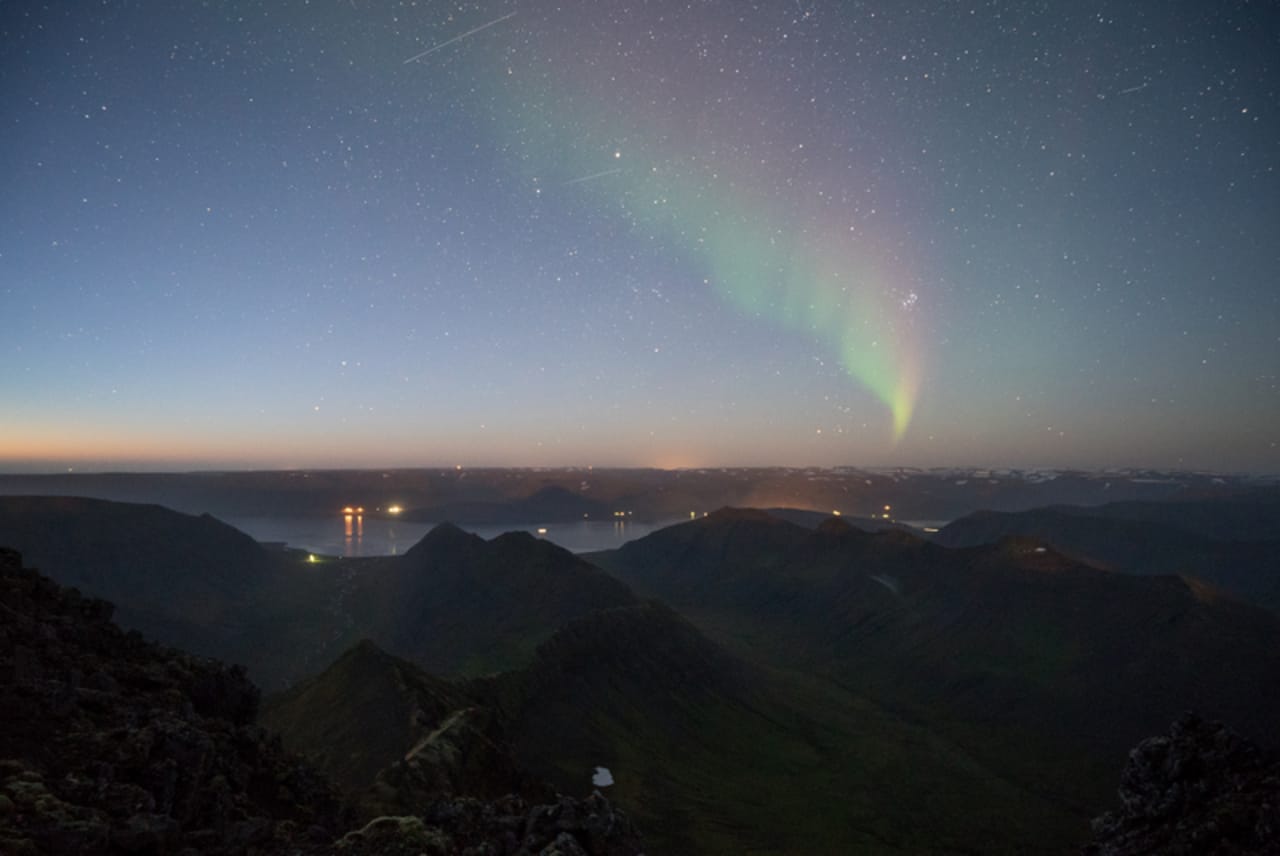 Northern lights above dark ridges near Kaldbakur in the Westfjords Alps.
