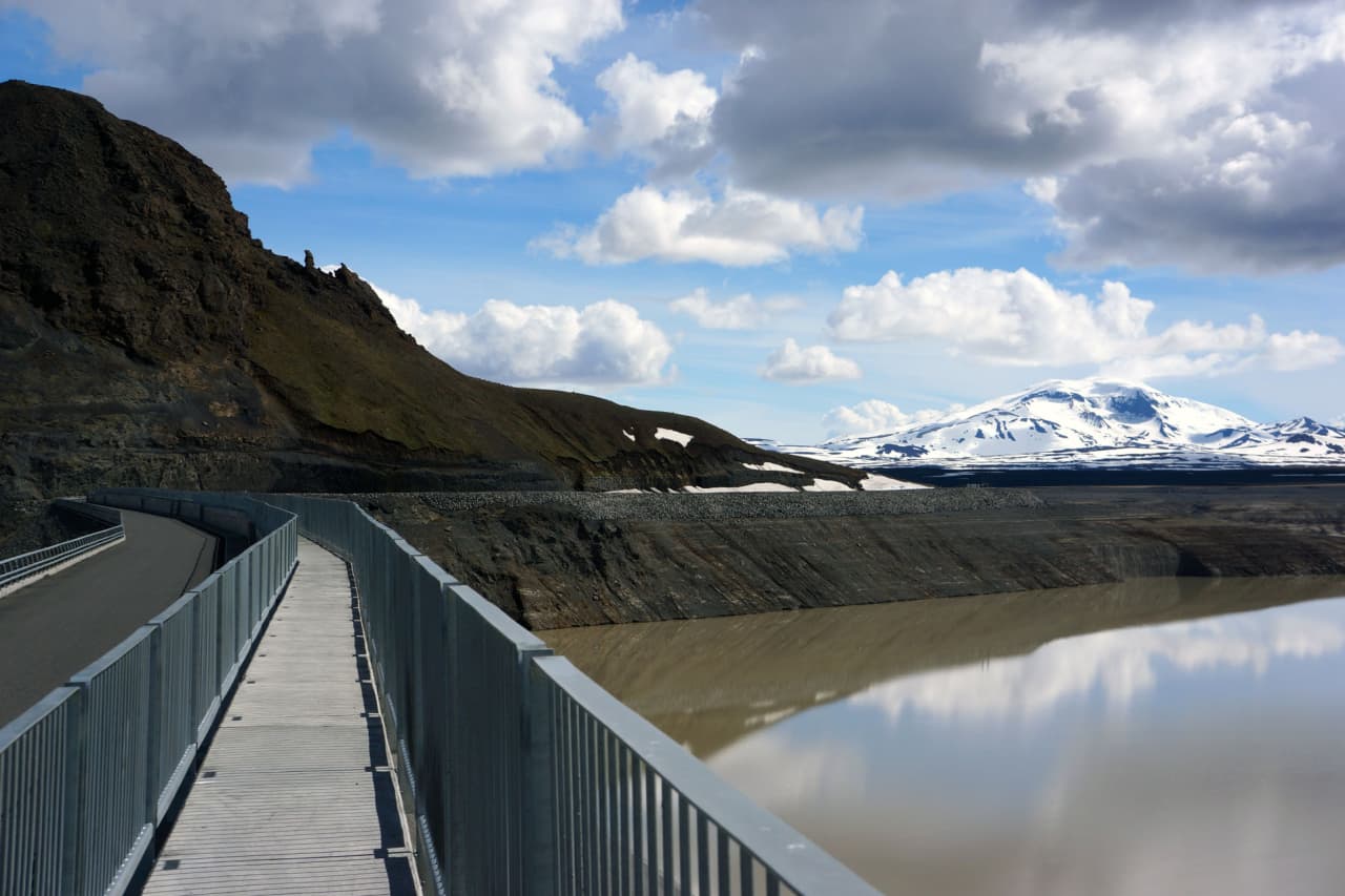 Walkway across Kárahnjúkavirkjun dam with Hálslón reservoir and Snæfell mountain in the distance.