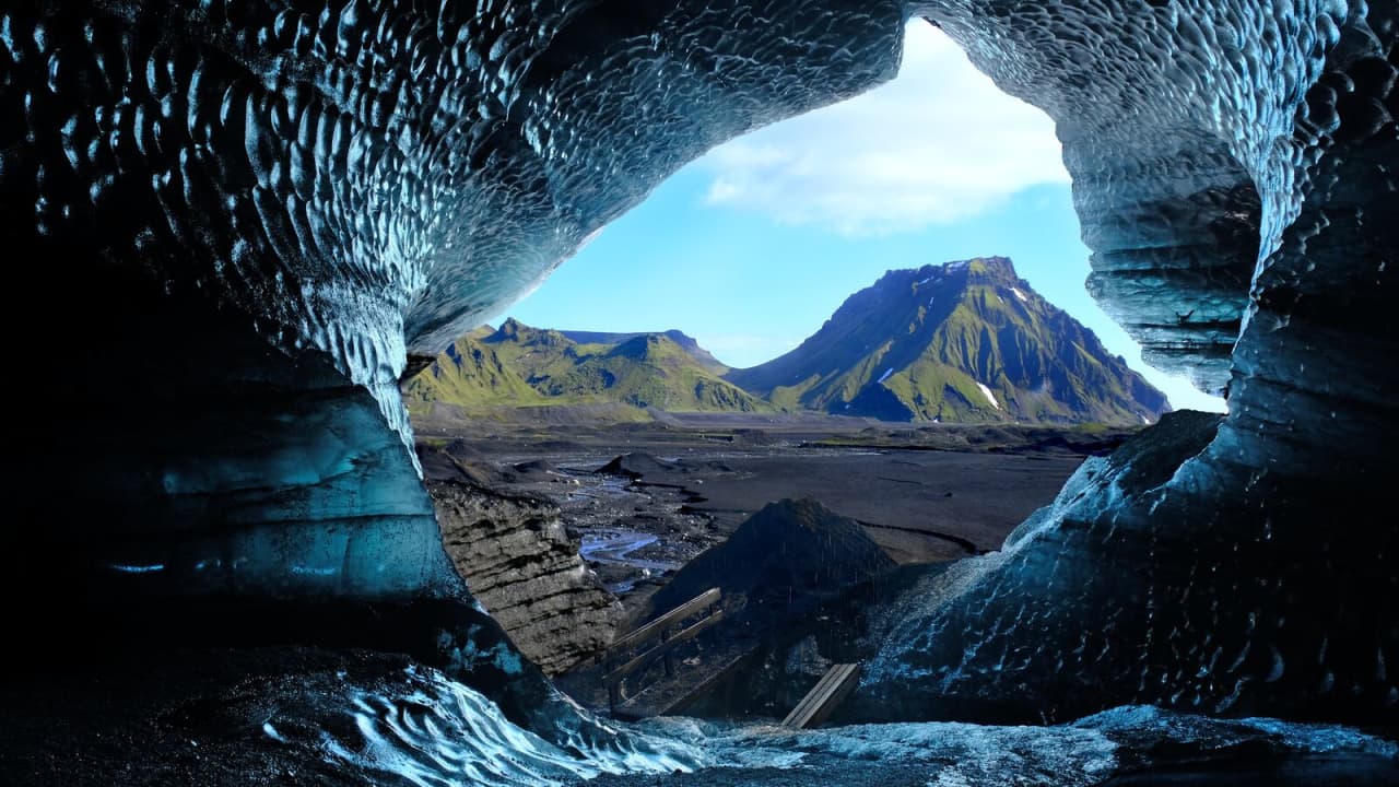 View from inside a dark Katla ice cave toward the Mýrdalsjökull landscape