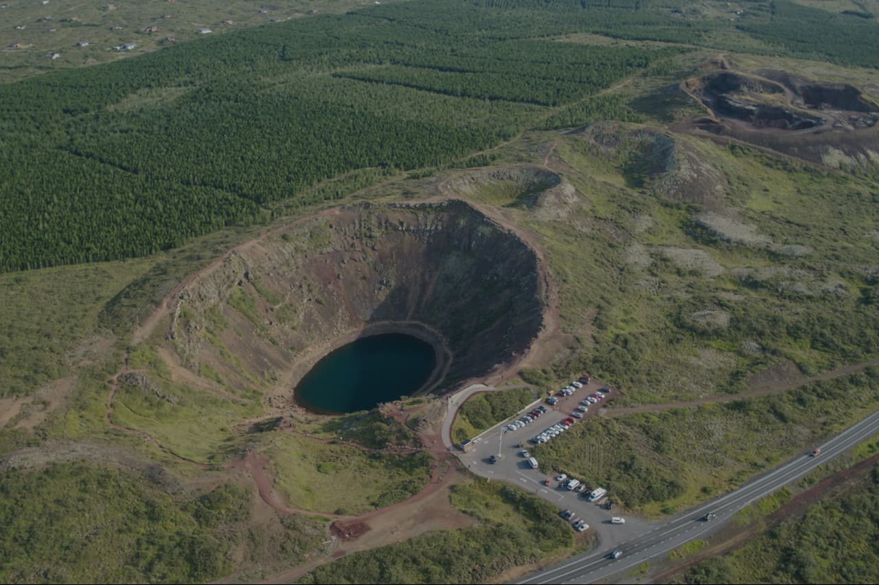 Aerial view of Kerið Crater with the nearby parking area and Golden Circle road context visible.