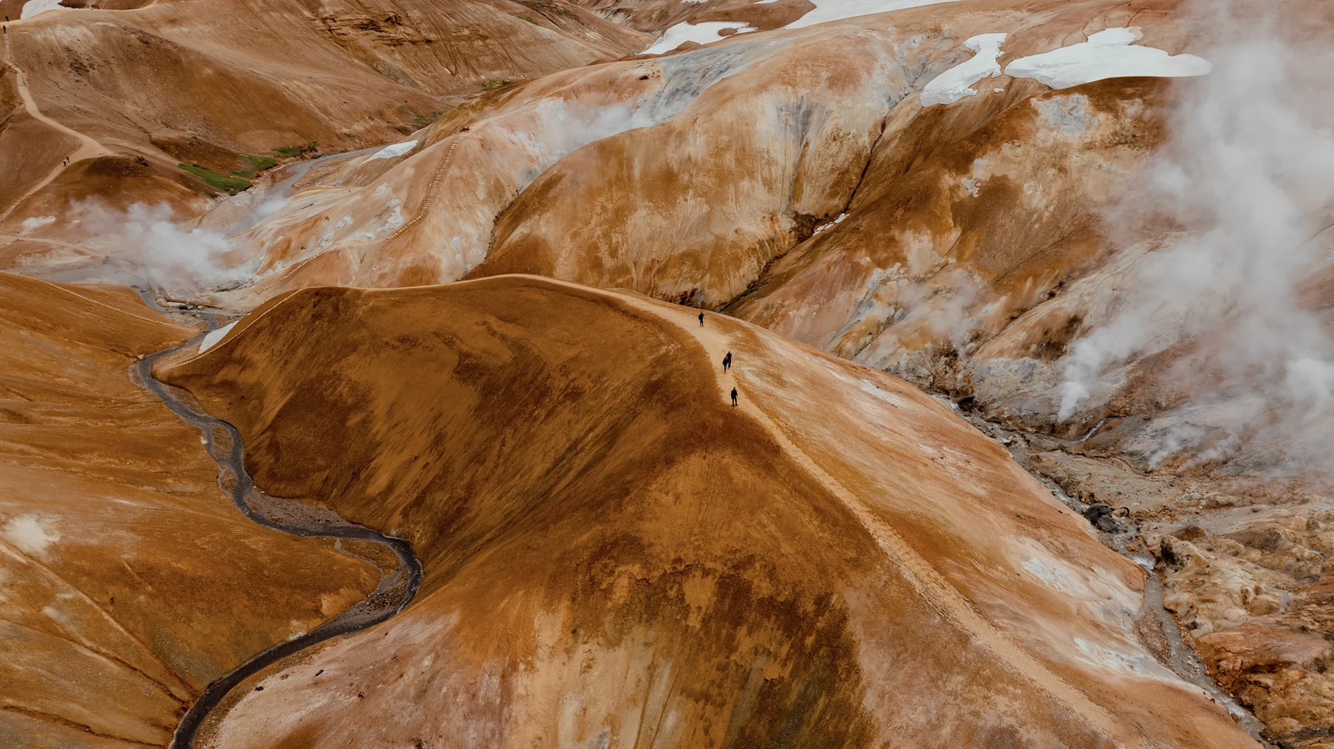 Hveradalir geothermal slopes in Kerlingarfjöll with pale trails, steam, and colorful mountain ridges.