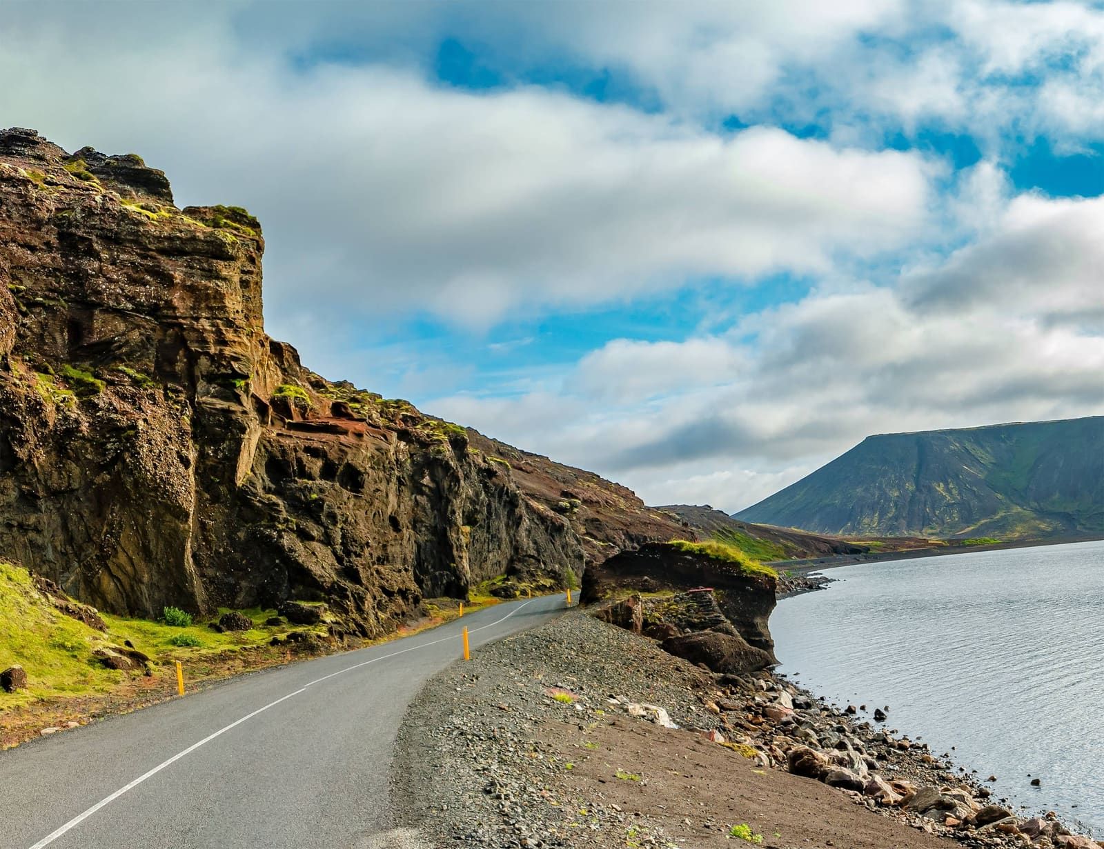 Road 42 curving beside Kleifarvatn with dark volcanic slopes above the lake.