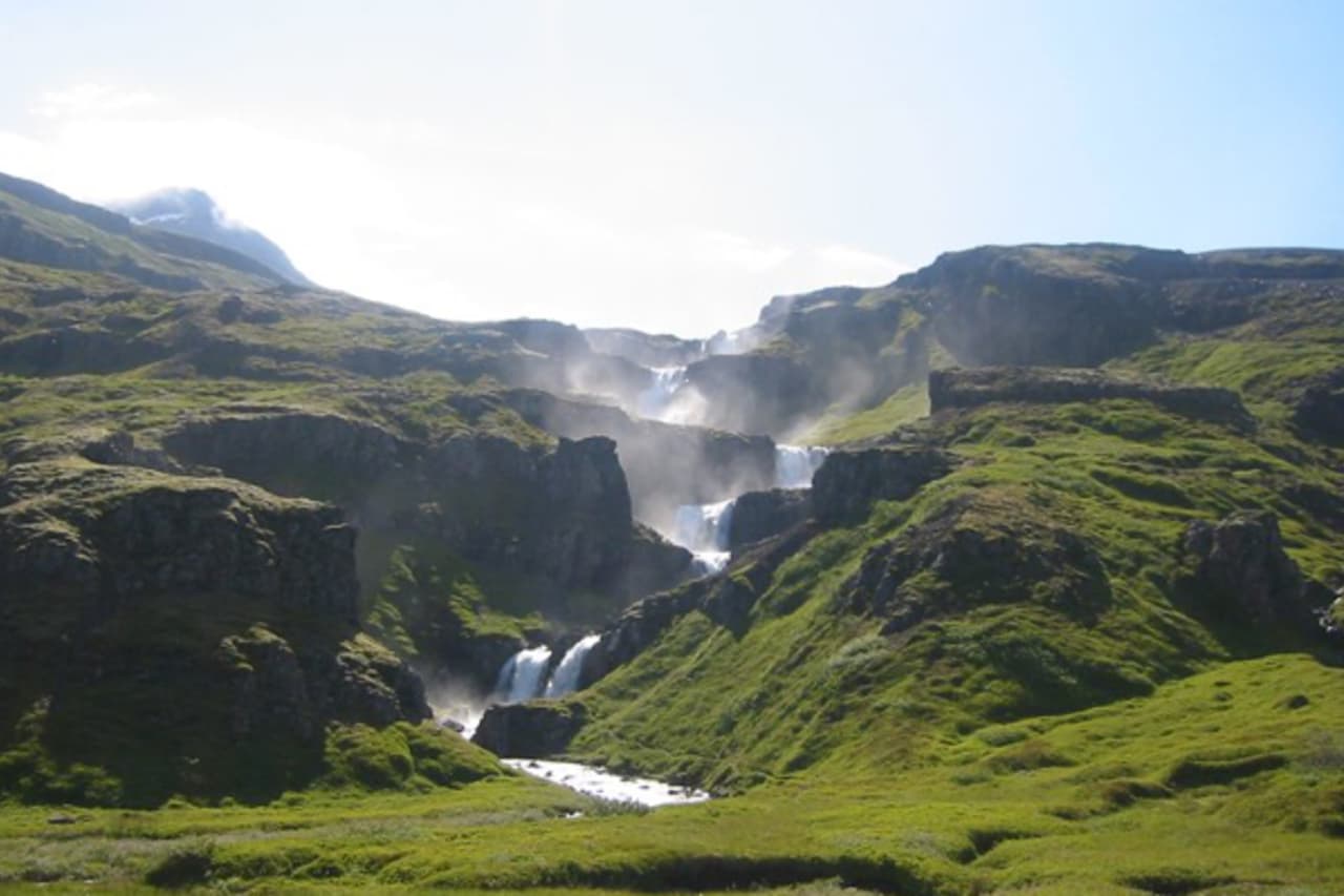 Klifbrekkufossar Waterfalls stepping down green cliffs in Mjóifjörður, East Iceland.