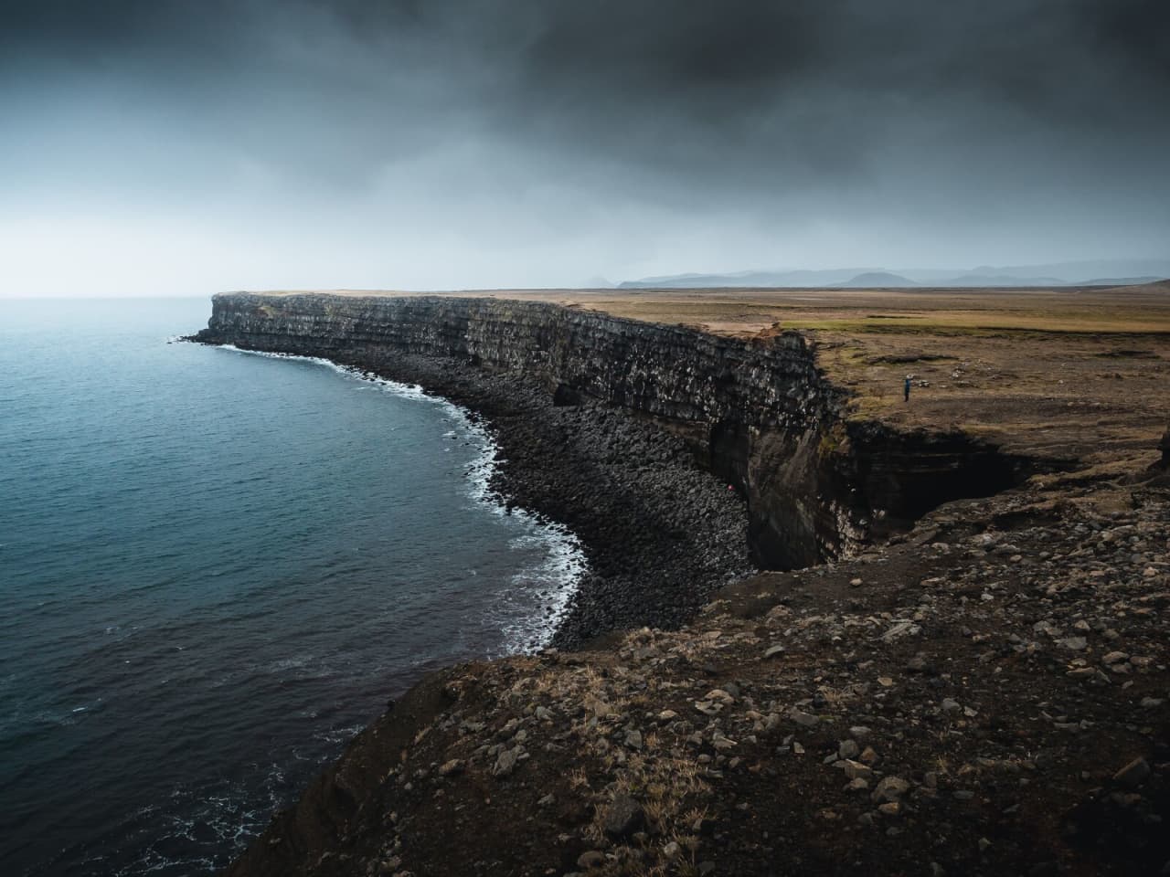 Grassy clifftop and dark sea stacks along the Krýsuvíkurbjarg coastline.