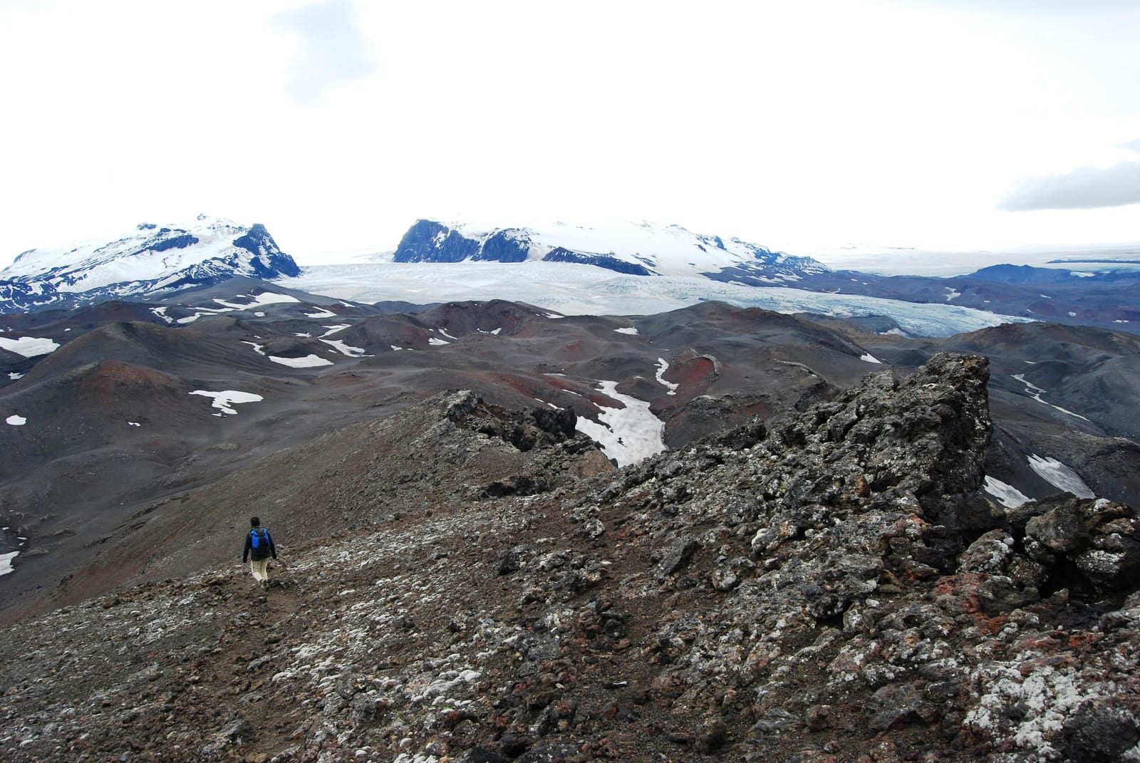 Rocky Biskupsfell hiking terrain in Kverkfjöll with dark ridges, snow patches, and broad glacier views.