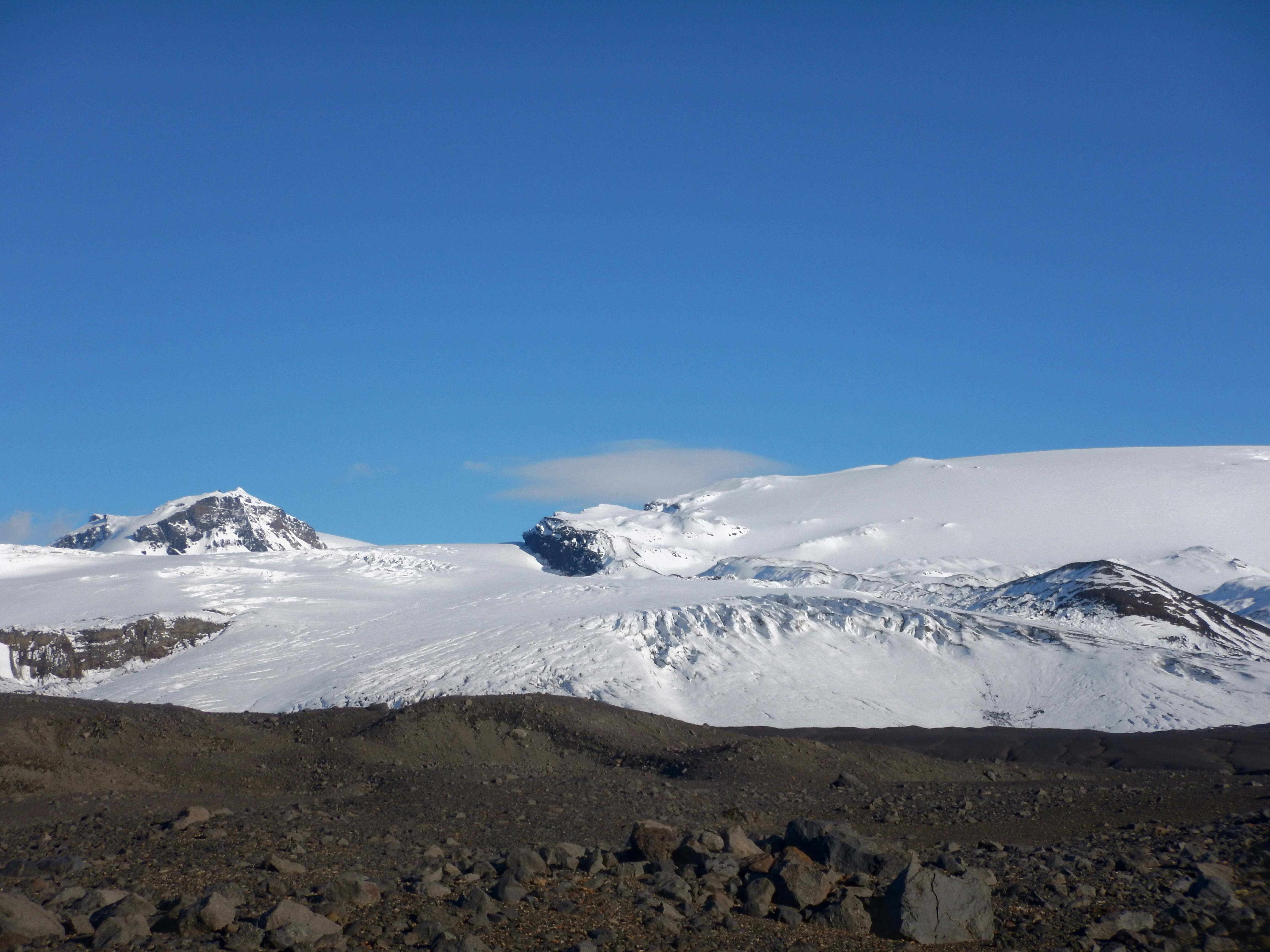 Snow-covered Kverkfjöll glacier and dark volcanic foreground under a clear blue sky.