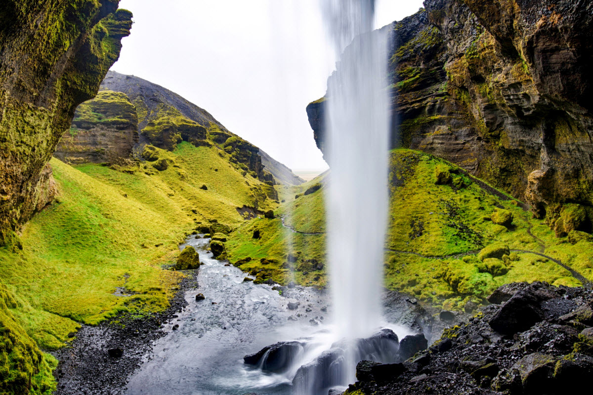 View from behind Kvernufoss with the waterfall dropping in front of the canyon.