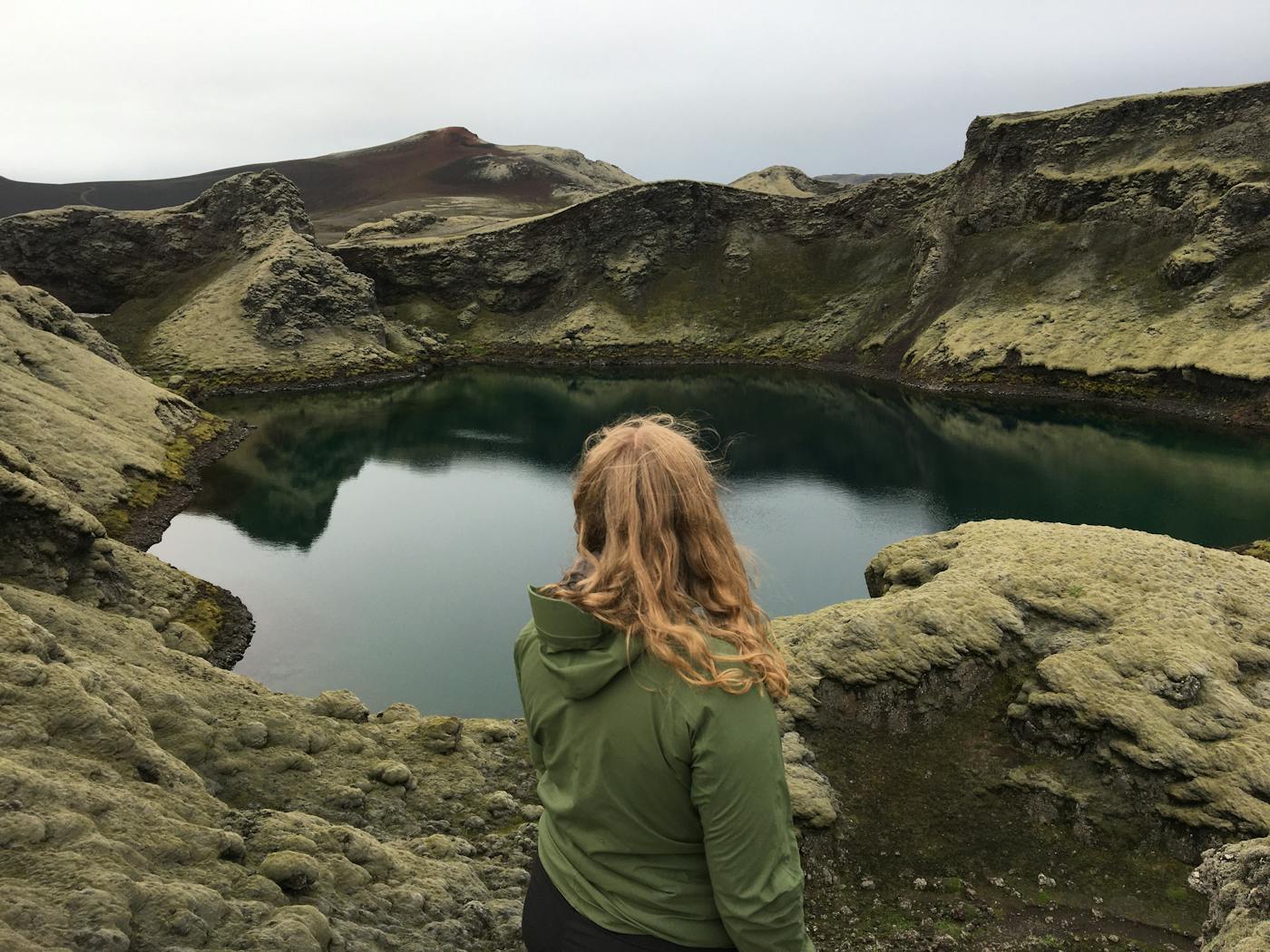 Tjarnargígur crater lake in the Lakagígar area with dark volcanic slopes and green moss around the water.